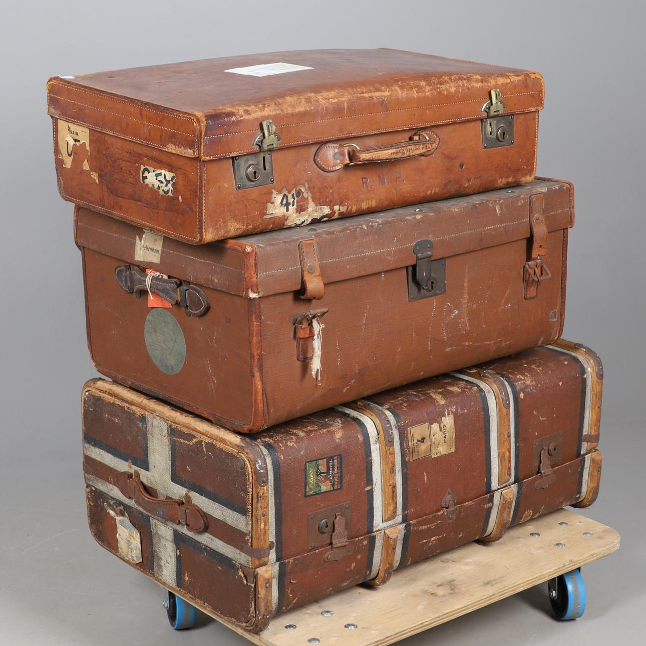 A VINTAGE STEAMER TRUNK, A HIDE COVERED SUITCASE, AND ANOTHER TRUNK.