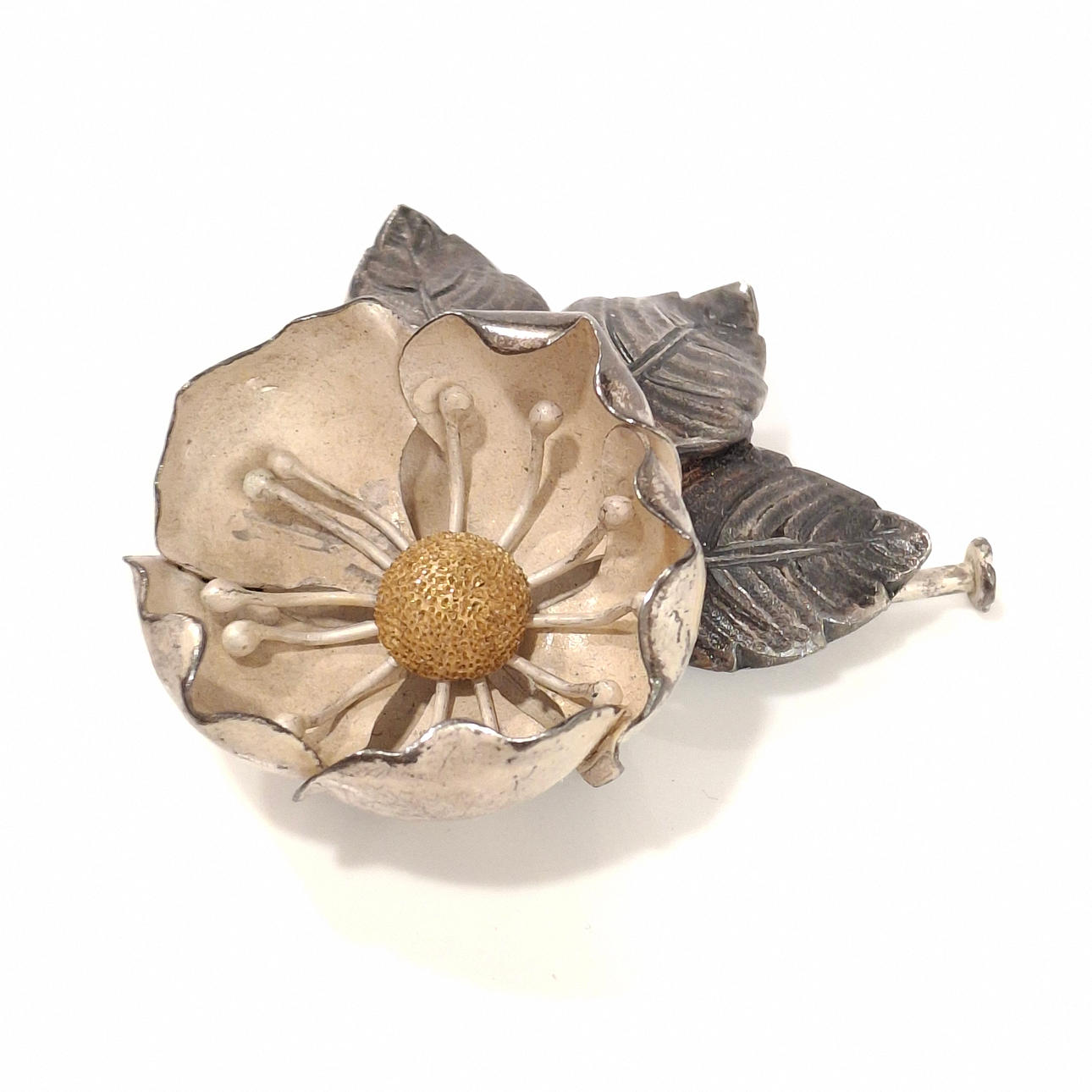 Gemeißelte und getönte silberne Blumenbrosche mit Blattdetail.