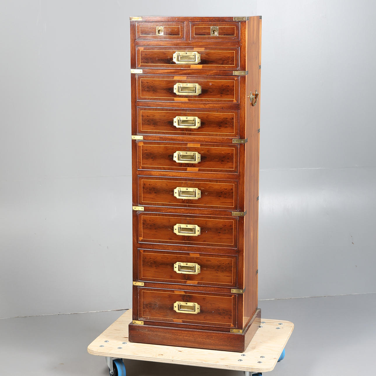 EINE EIBENHOLZFURNIERTE KOMMODE IM KAMPAGNENSTIL MIT SCHMALEN PROPORTIONEN.