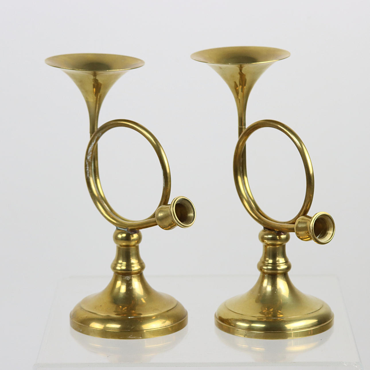 Un par de candelabros con forma de trompeta de latón.