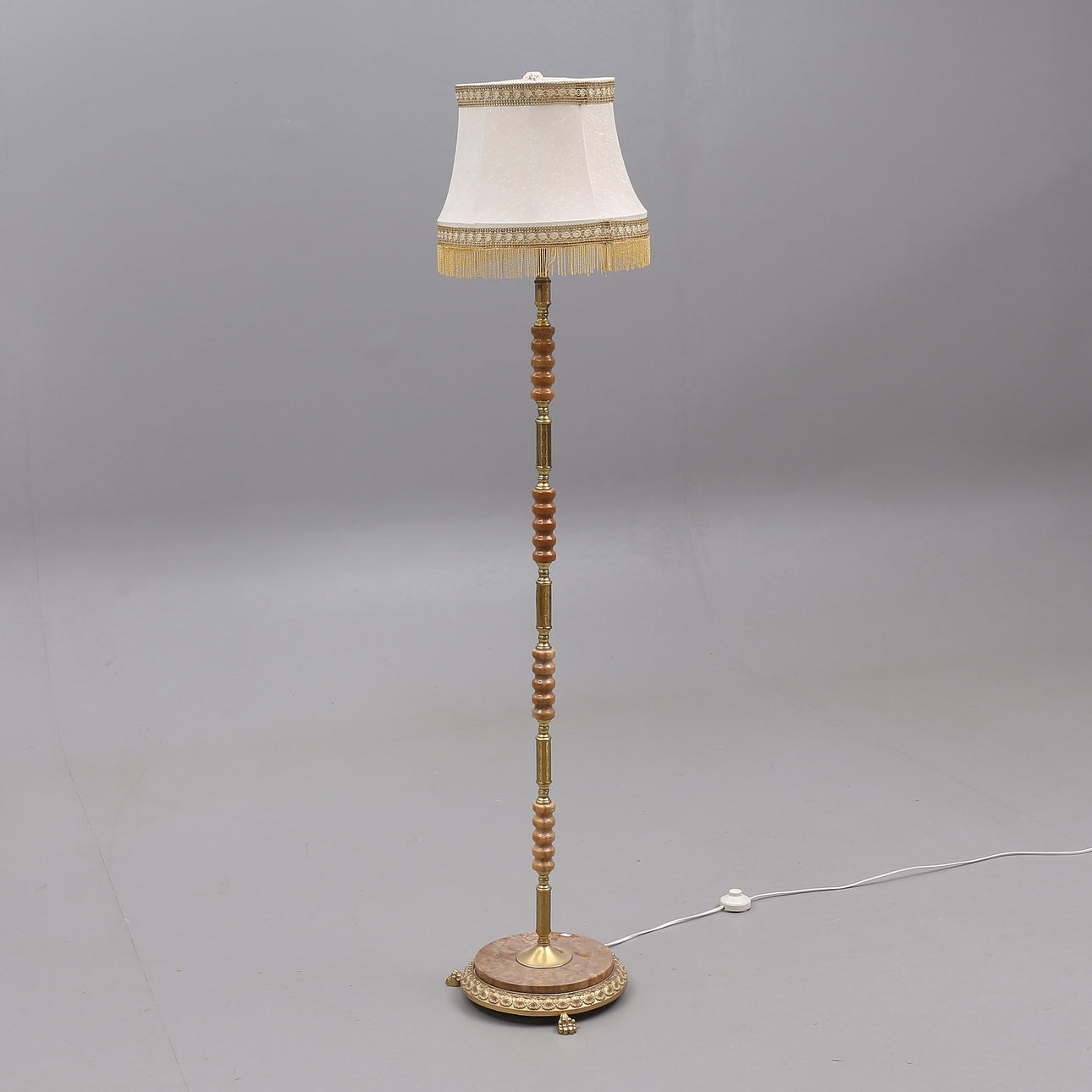 A floor lamp, yellow metal with stone base, later part of the 20th century.