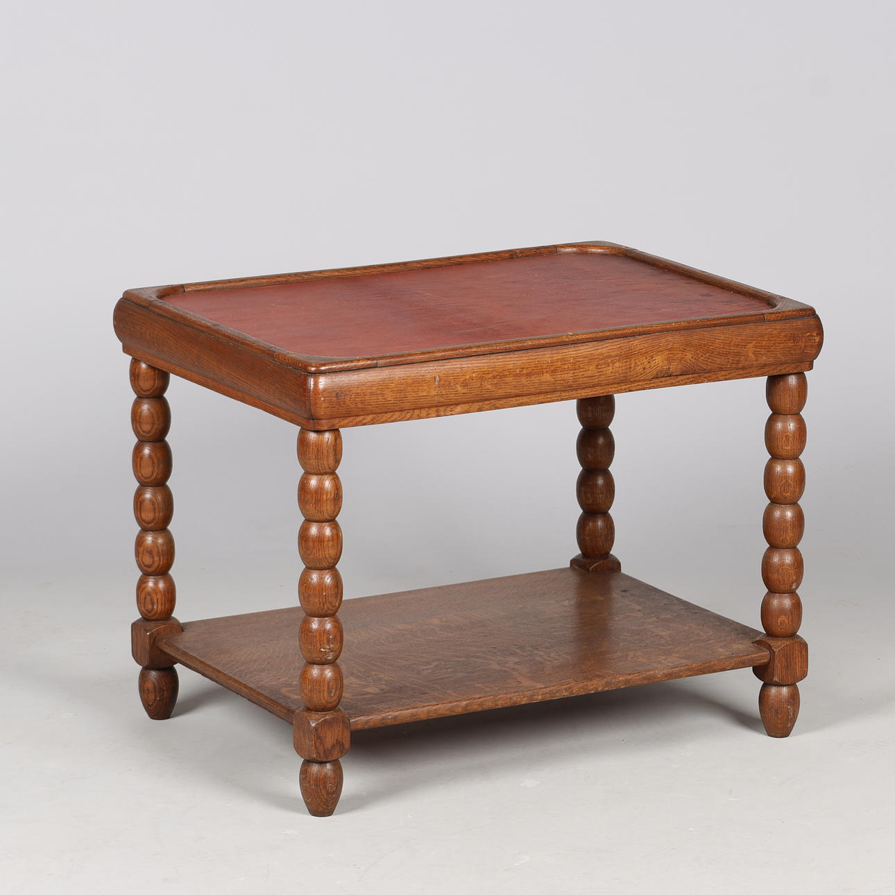 Coffee table with 'bobbin' legs and bottom shelf, oak frame and top top upholstered in leather, European designer, first half of the 20th century.