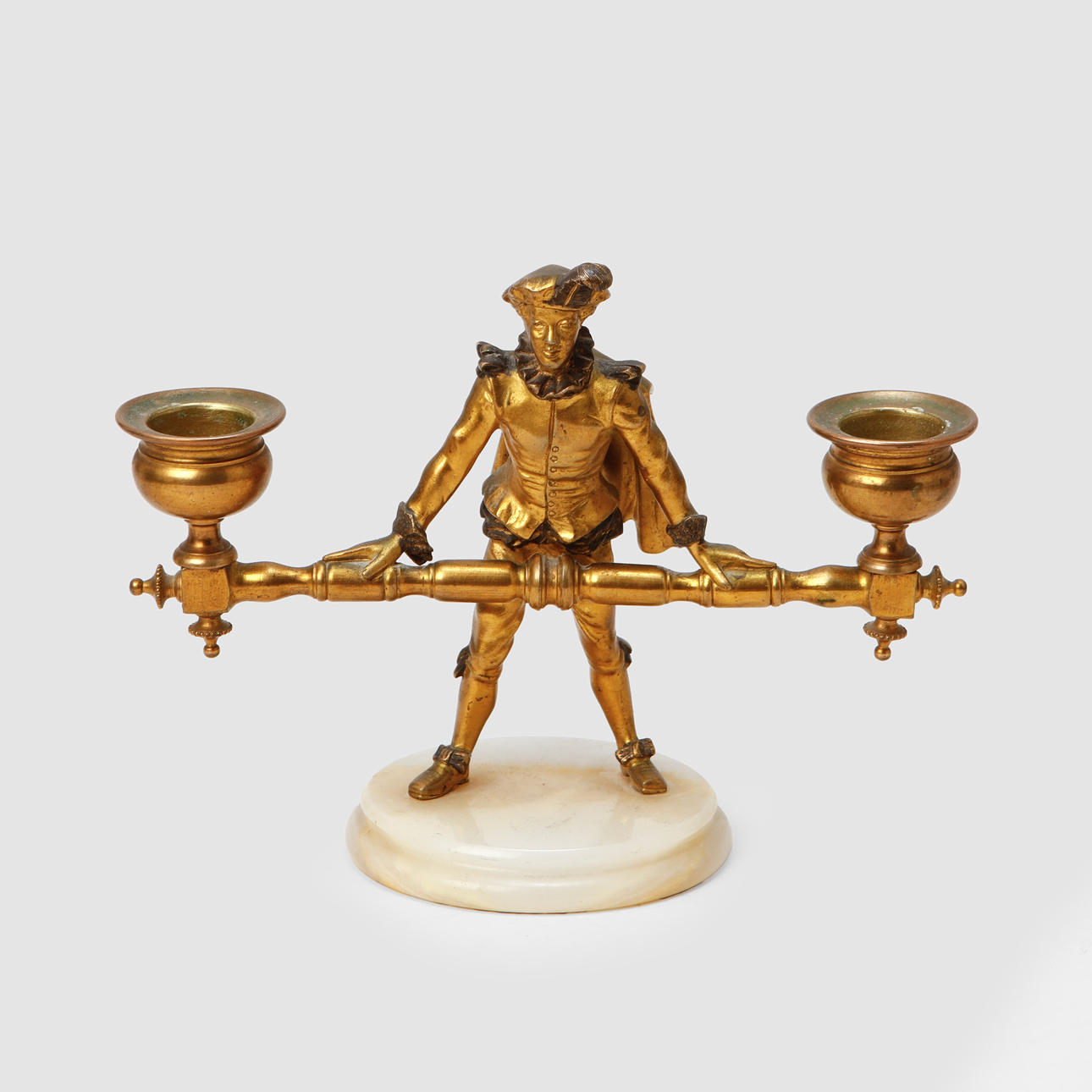 A brass candlestick on a marble plinth, 18th/20th century.