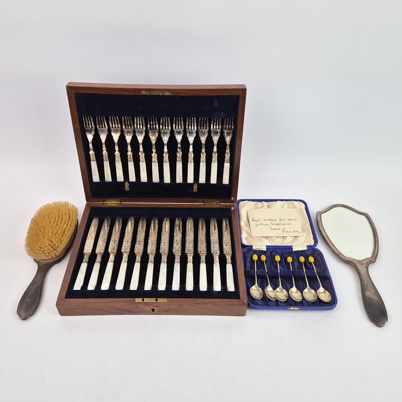 A BOXED SET OF SILVER-PLATED FISH AND FORK KNIVES, A SET OF COFFEE SPOONS AND A SILVER CLAD HAIRBRUSH AND MIRROR. (4).