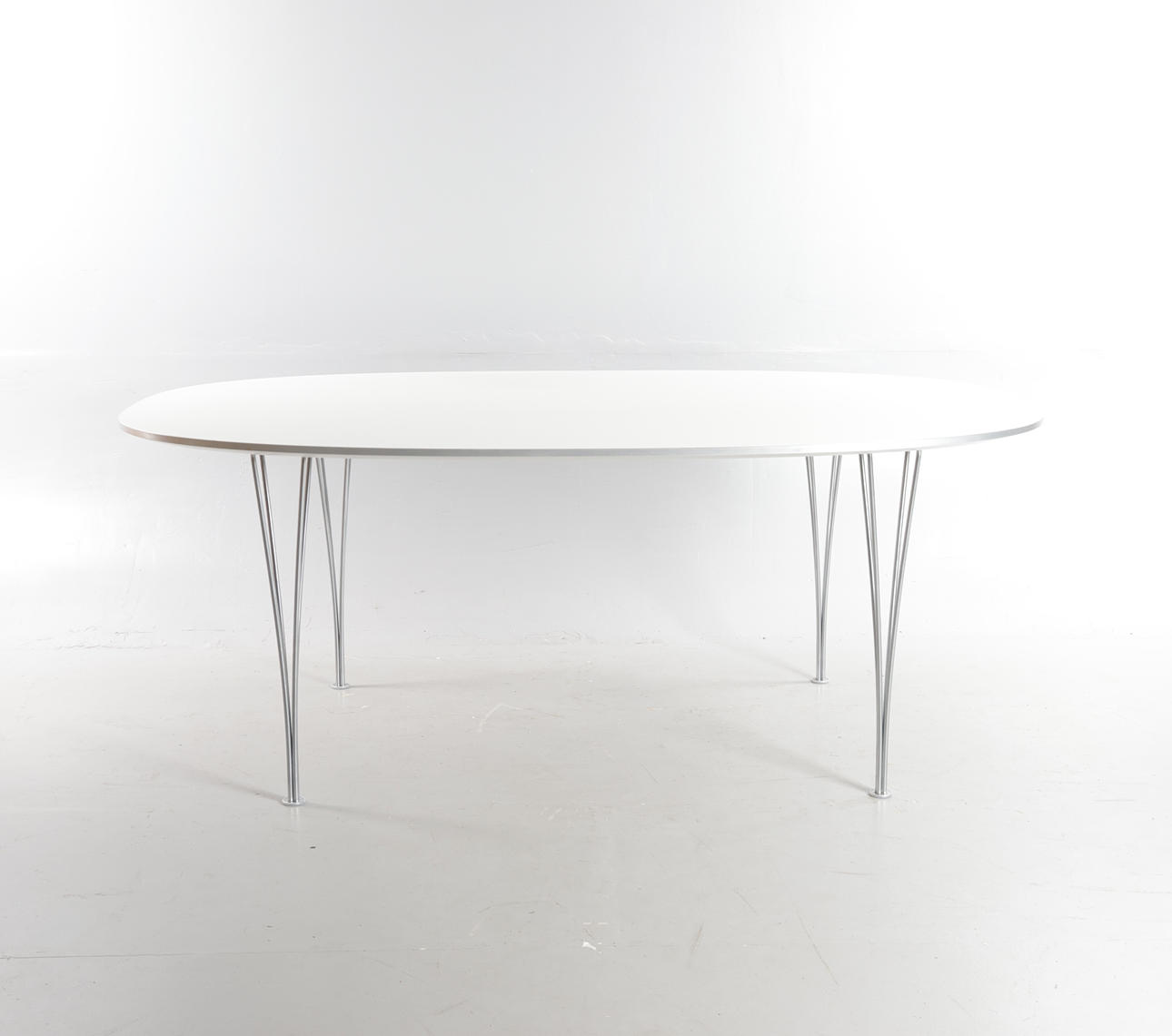 PIET HEIN & BRUNO MATHSSON. Superellipse dining table with white laminate top with brushed aluminum edging, mounted with chrome-plated steel tension legs. Manufactured and branded at Fritz Hansen.