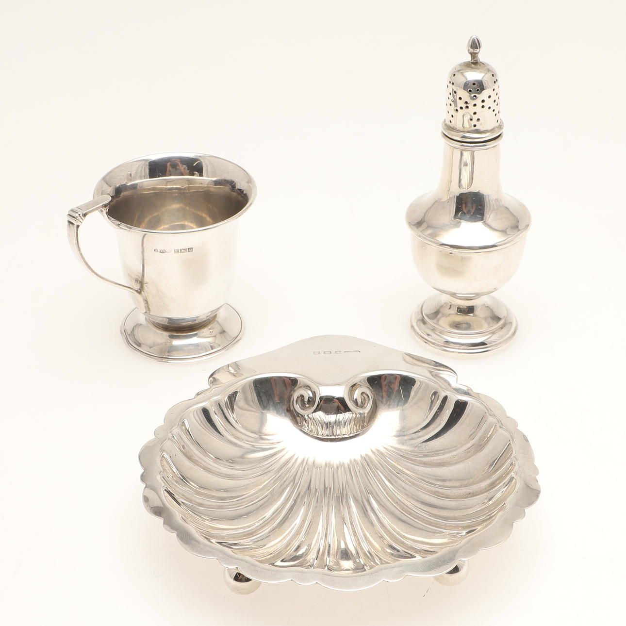 A SILVER SCALLOP SHELL DISH, SHAKER AND CHRISTENING CUP.