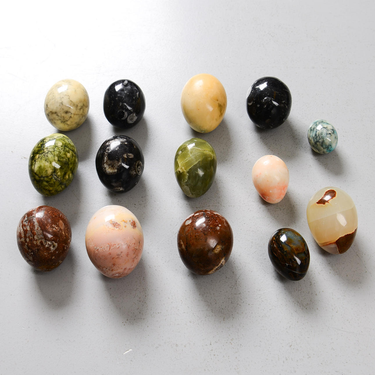 A set of 18 stone eggs, different types of stone.