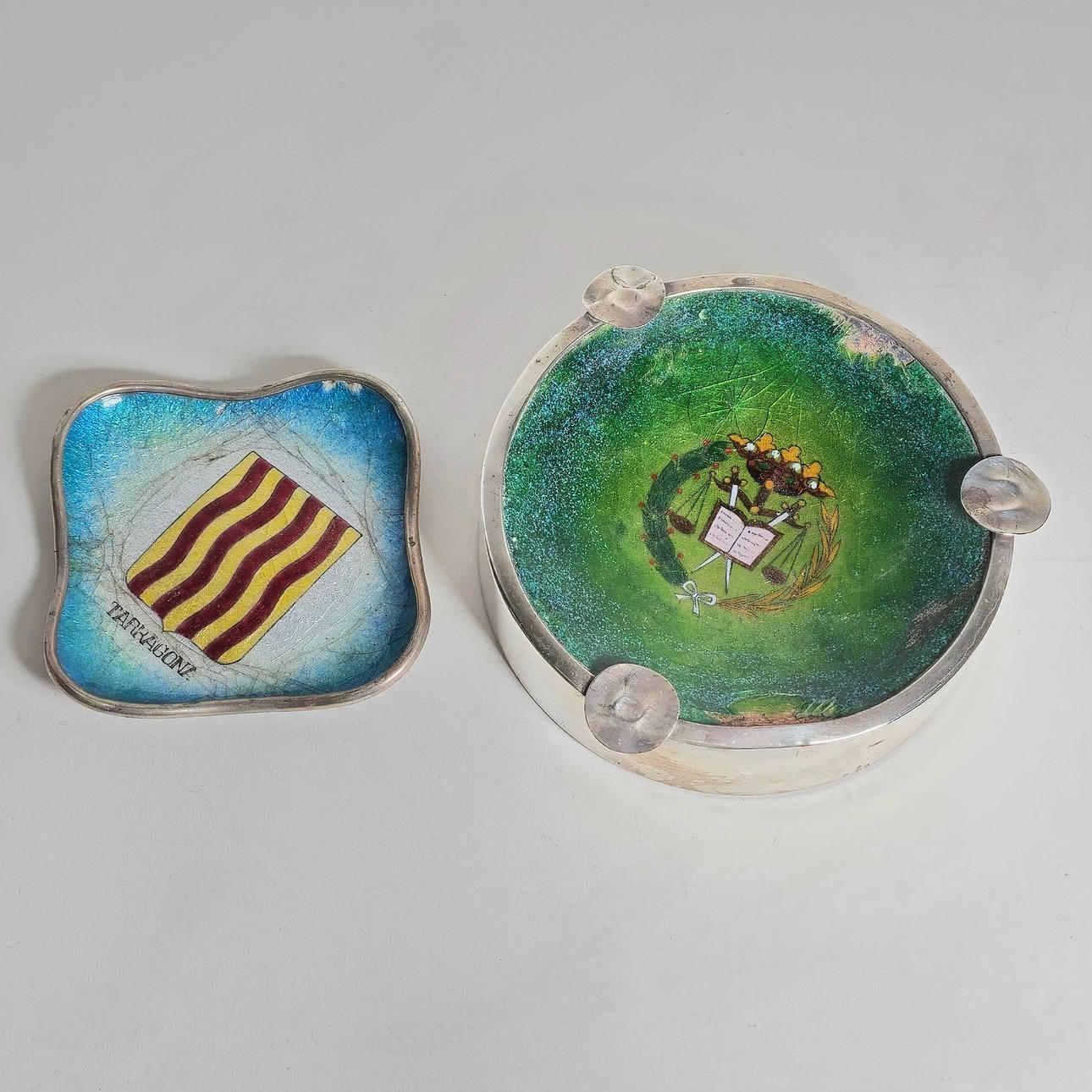 TWO SILVER ASHTRAYS WITH ENAMELED HERALDIC MOTIF.