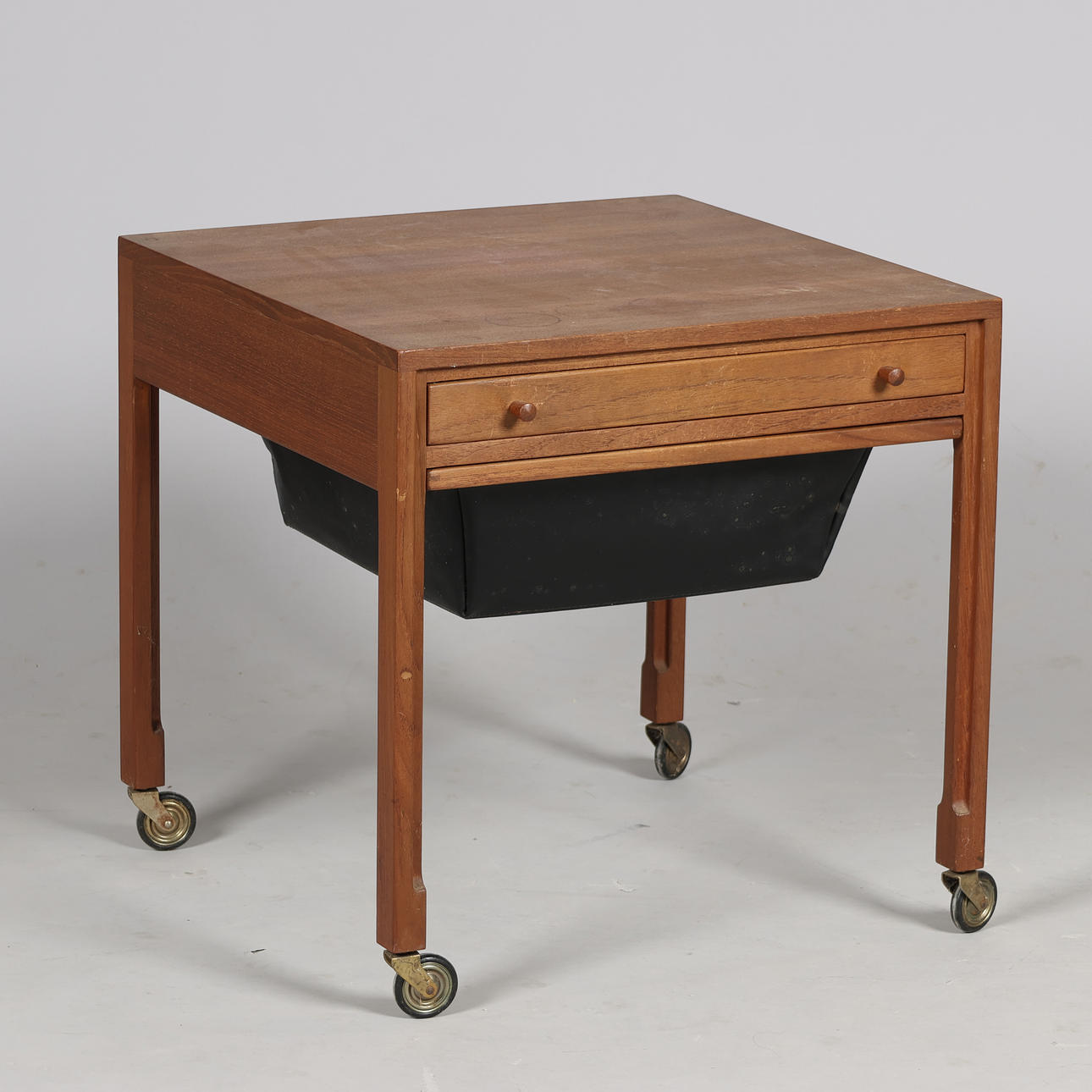 Sewing table of teak on wheels with drawer and pull-out basket in skai, Danish furniture manufacturer, Denmark, second half of the 20th century.
