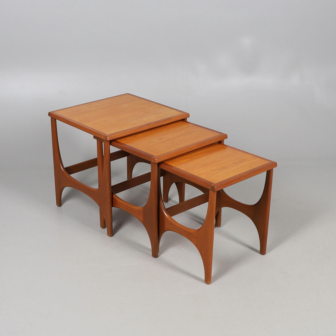 A NEST OF THREE TEAK TABLES.
