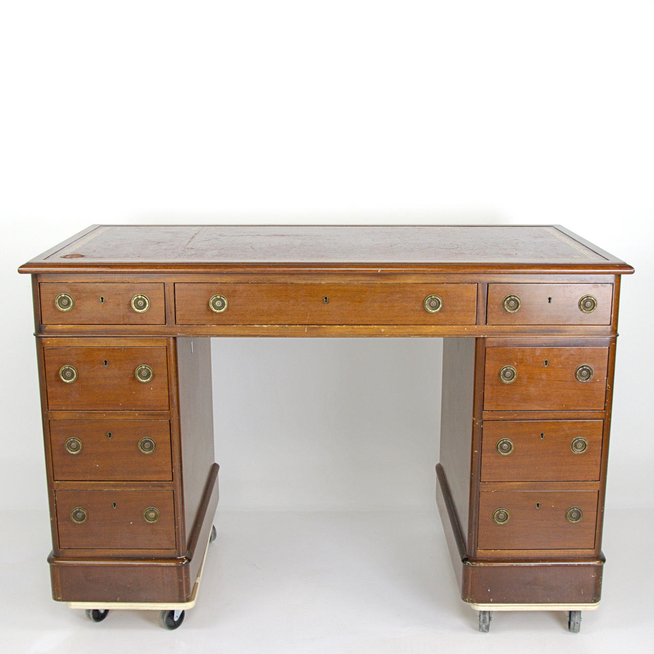 A DESK, mahogany veneer, writing surface covered with leather with embossed pattern, brass fittings, English style, 20th century.