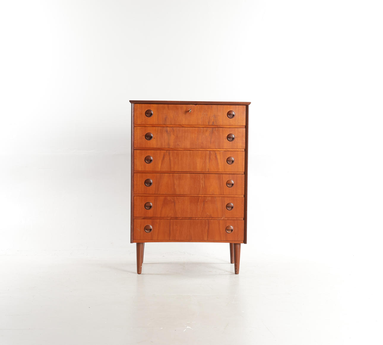 DANSK MØBELDESIGN. Teak chest of drawers, front with six drawers with round handles, round tapered legs. Denmark, 1960s.