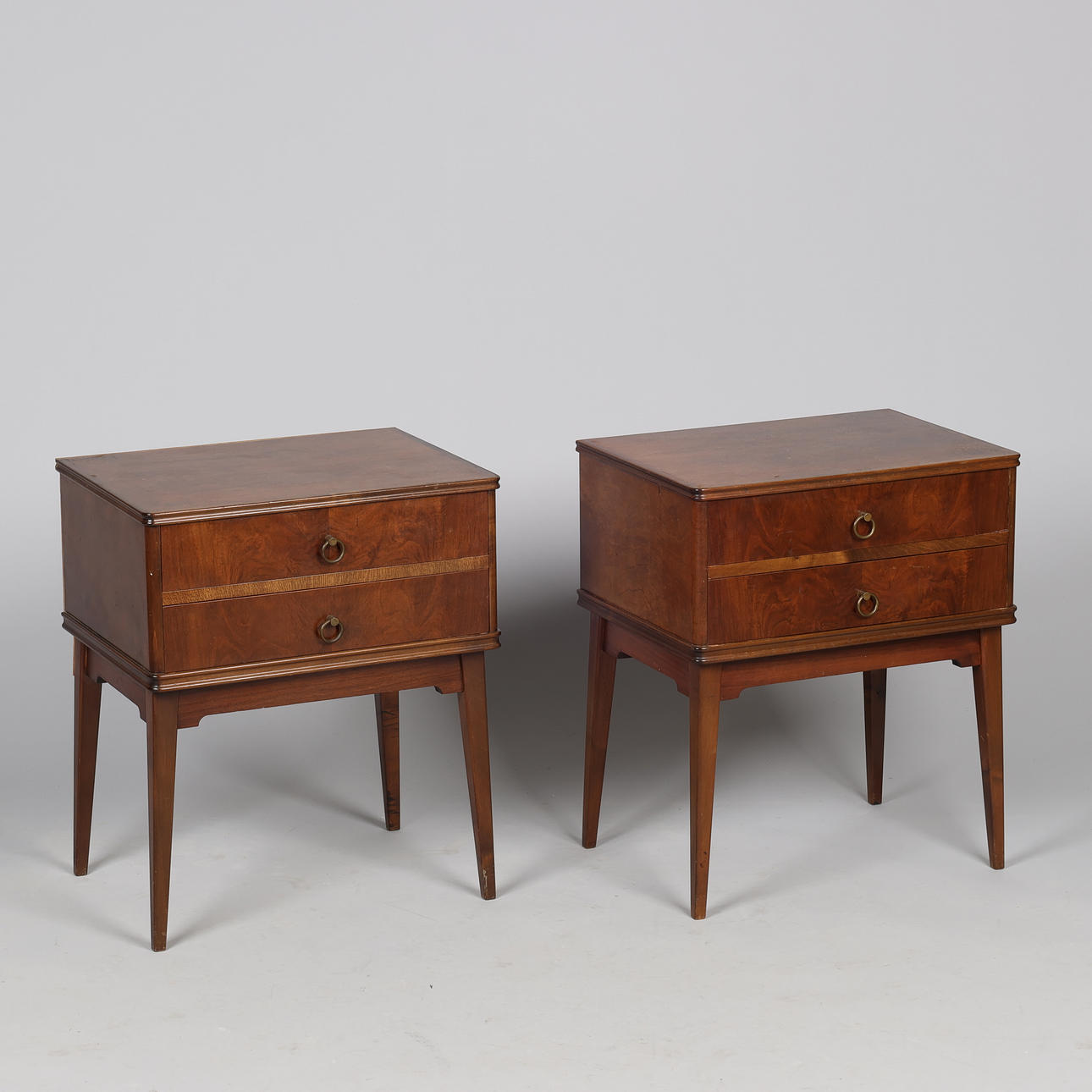 A pair of walnut bedside tables with two drawers and handles of patinated brass, first half of the 20th century (2).