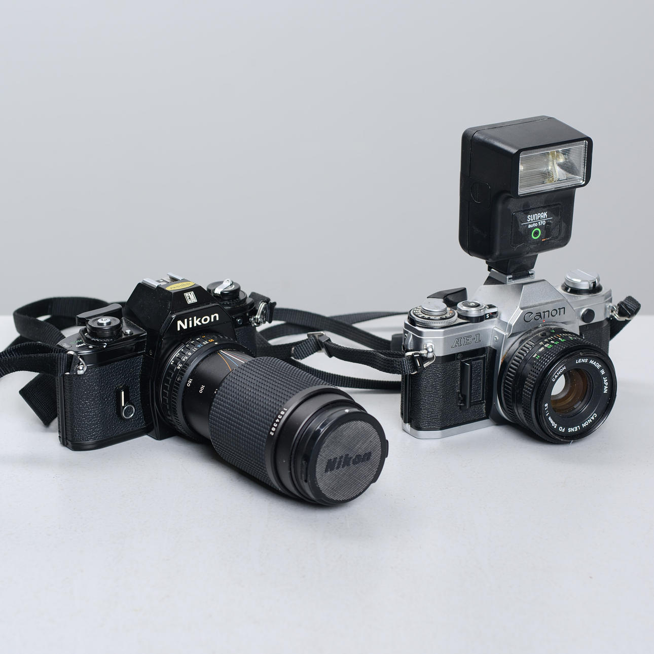 Mirror reflex cameras, 2 pcs, “Canon AE-1" & “Nikon EM”.