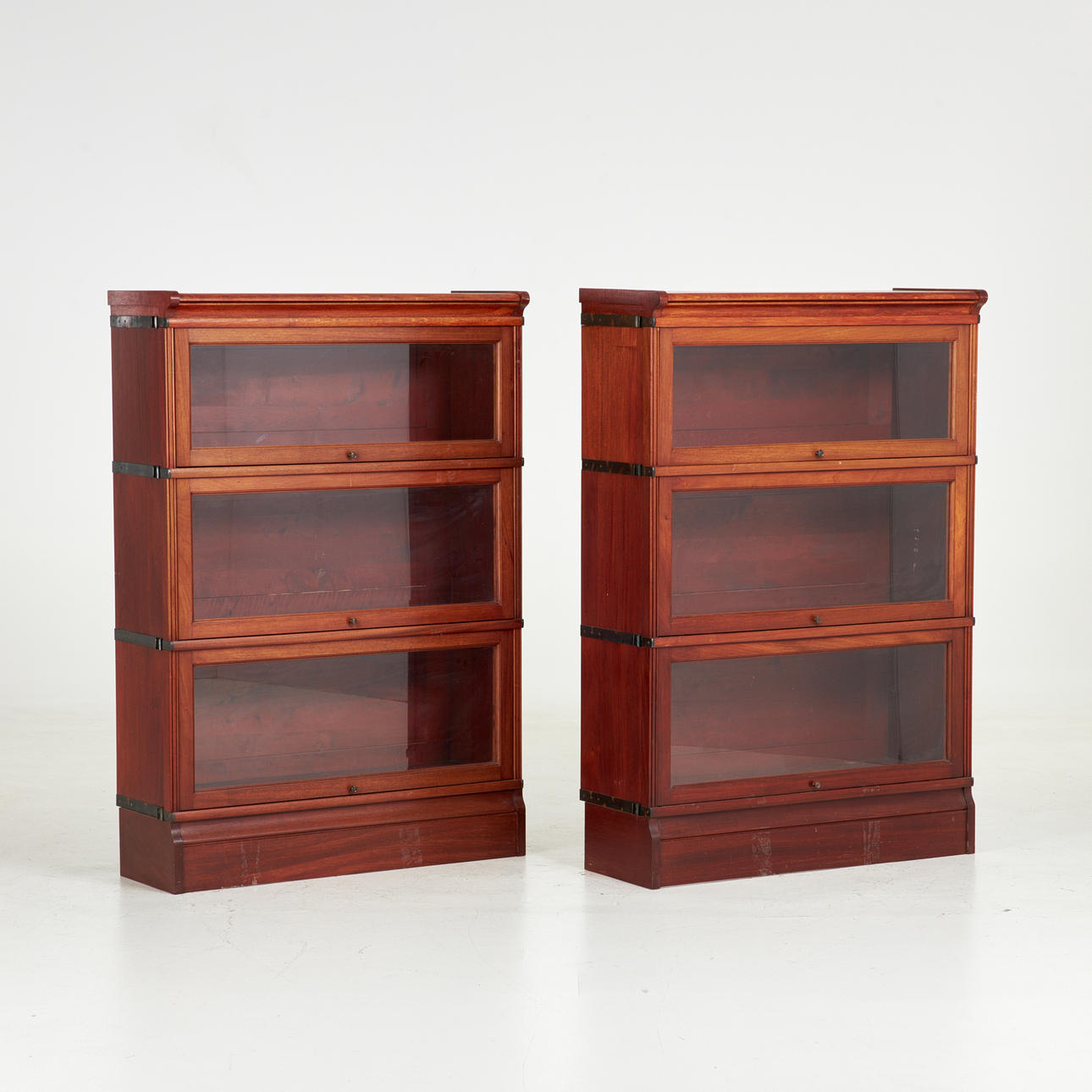 A pair of bookcases, later part of the 20th century, stackable modules with openable glass doors, metal fittings.