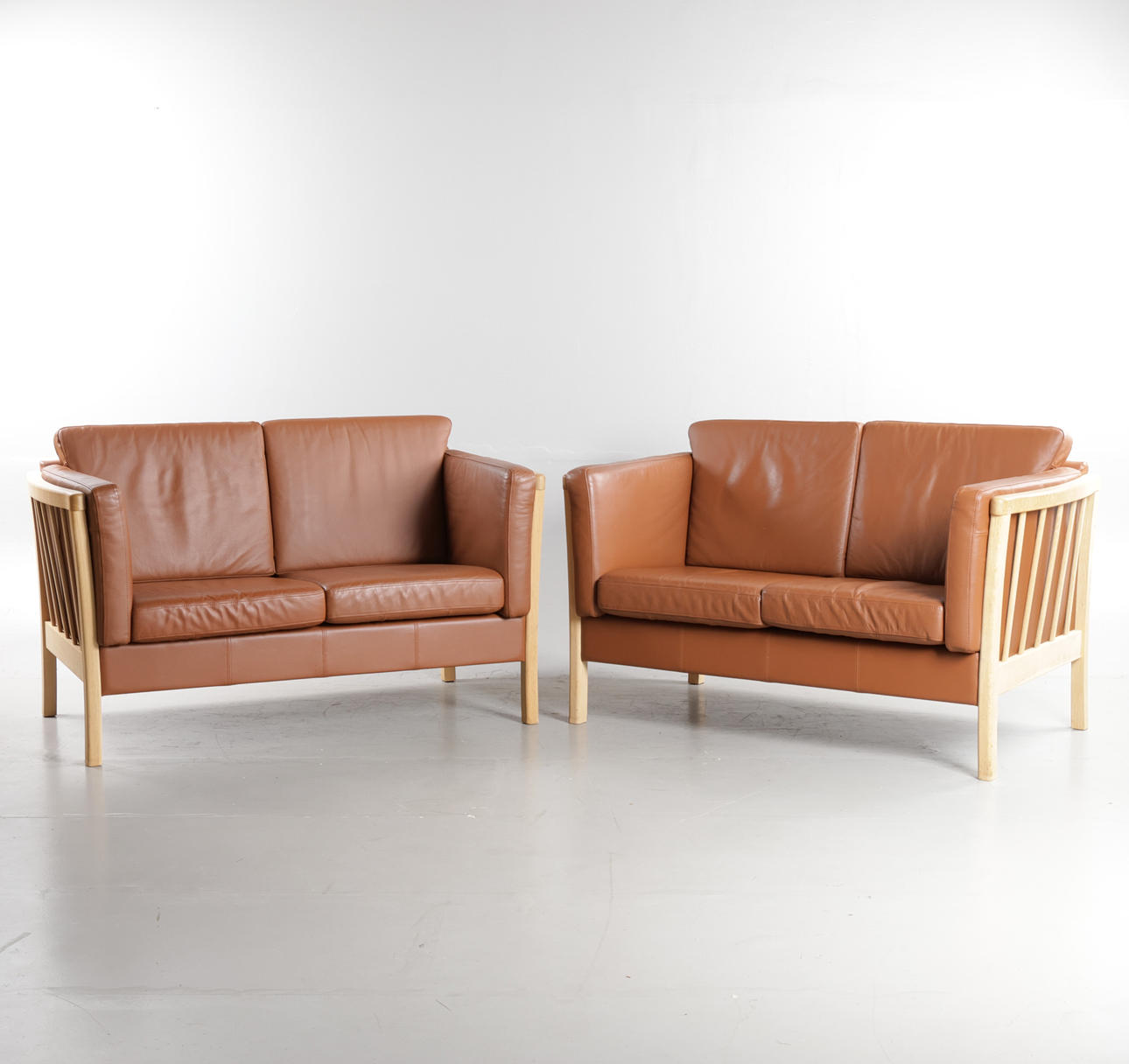 DANSK MØBELDESIGN. A pair of two-pers. sofas with oak frame, loose cushions upholstered in cognac leather. Made in Denmark (2).