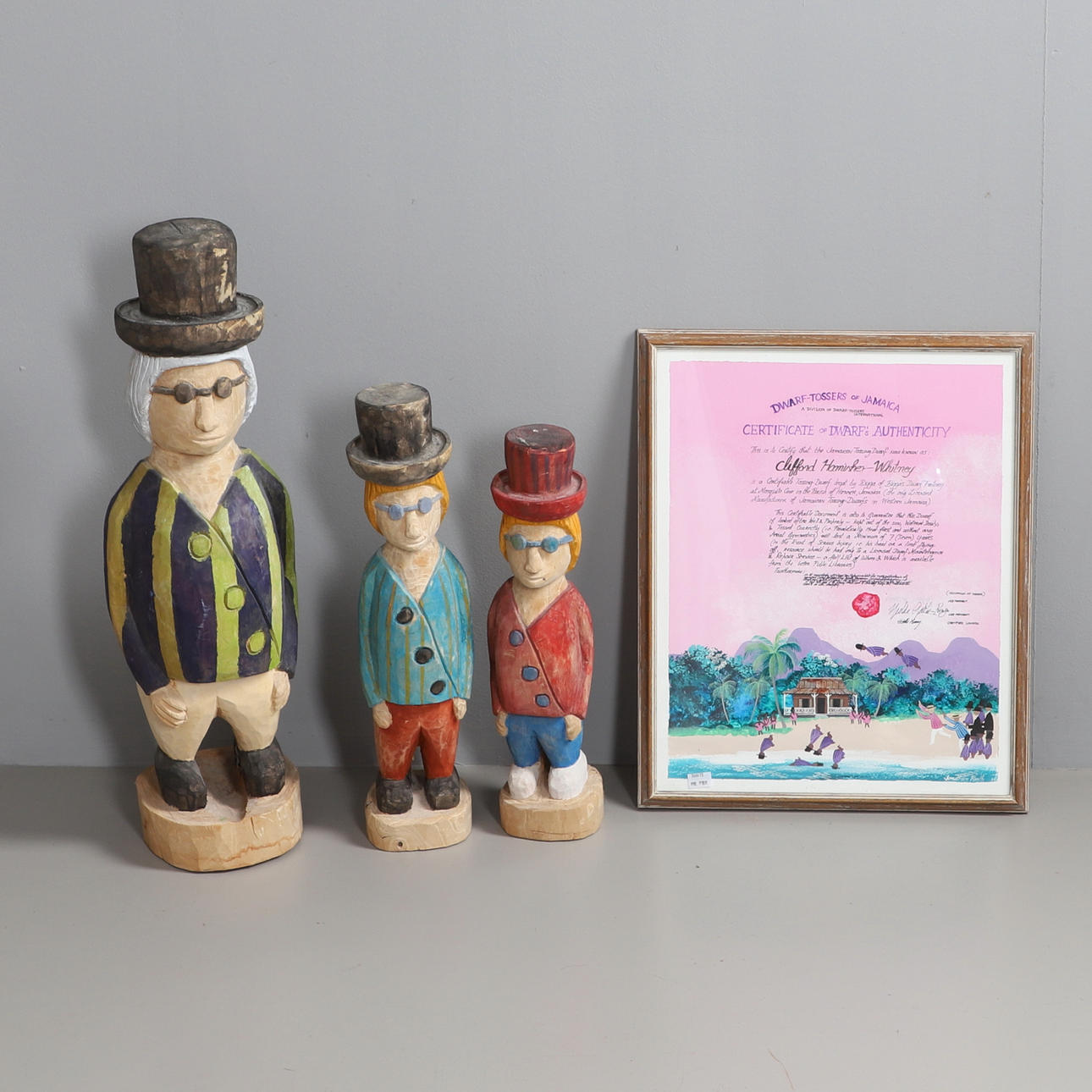 A FRAMED DWARF TOSSING CERTIFICATE AND THREE WOODEN DWARVES.