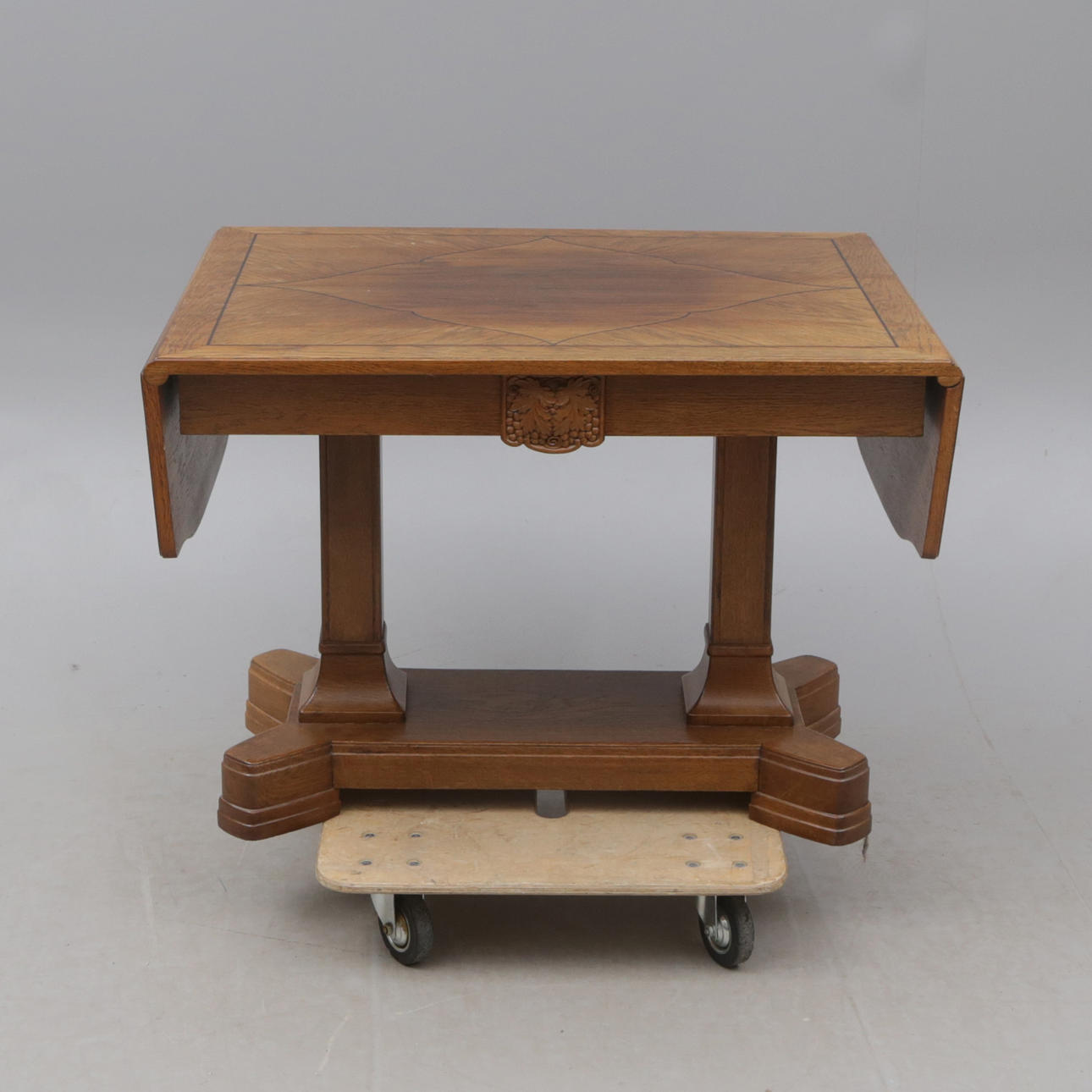 An oak folding table with grape relief, early 20th century.
