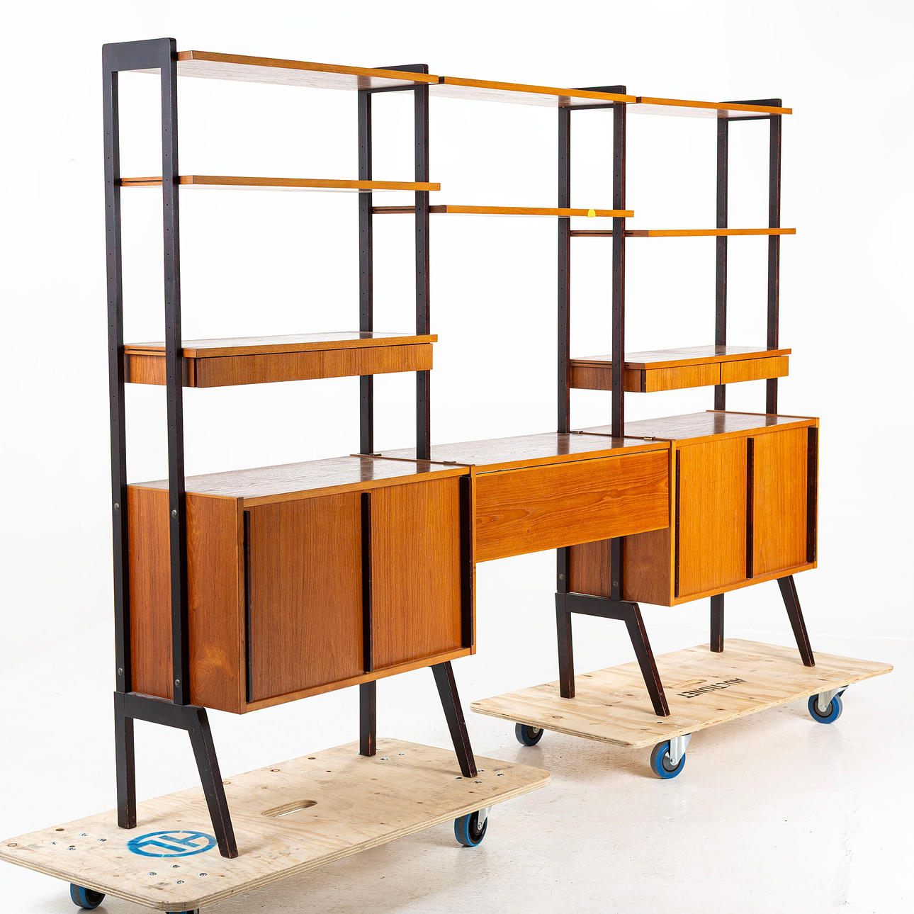 A mid 20th century shelving system, frame veneered in teak with blackened outer gables.