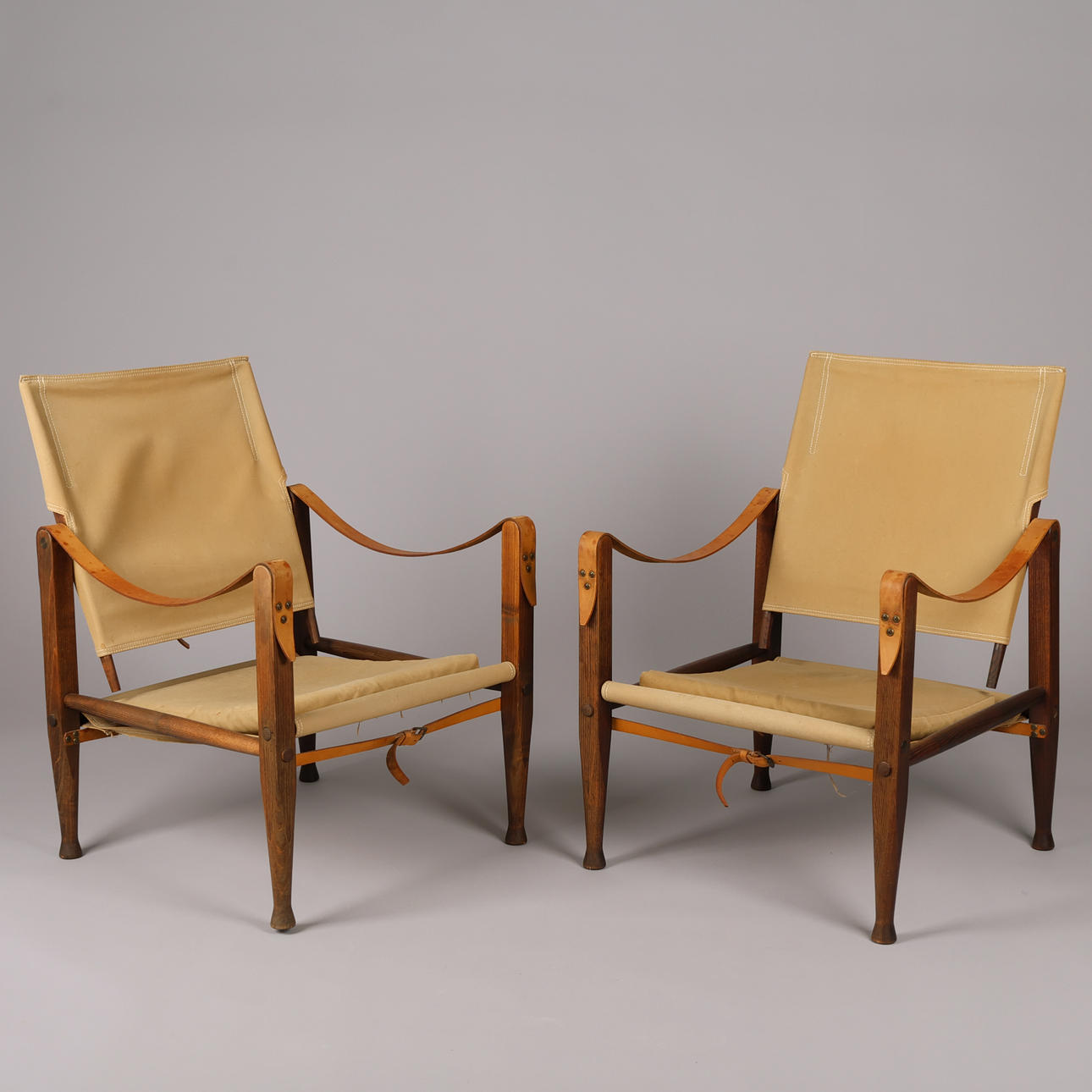 KAARE KLINT. A pair of 'safari' chairs with frame of smoked ash, upholstered in green canvas, armrests made of core leather, Rud. Rasmussen's joinery, Model 4700, Denmark, designed 1933 (2).