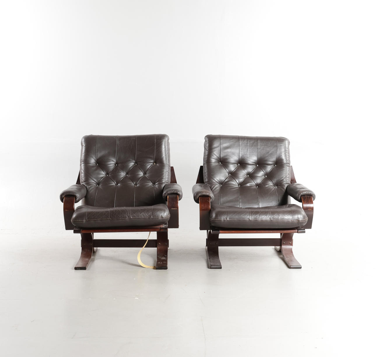 SKANDINAVISK MØBELDESIGN. A pair of armchairs with frames of dark-stained wood, upholstered in deep stapled leather, 1970-80s (2).