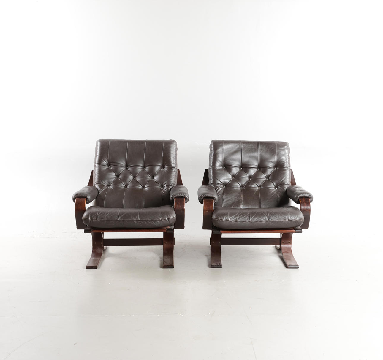 SKANDINAVISK MØBELDESIGN. A pair of armchairs with frames of dark-stained wood, upholstered in deep stapled leather, 1970-80s (2).