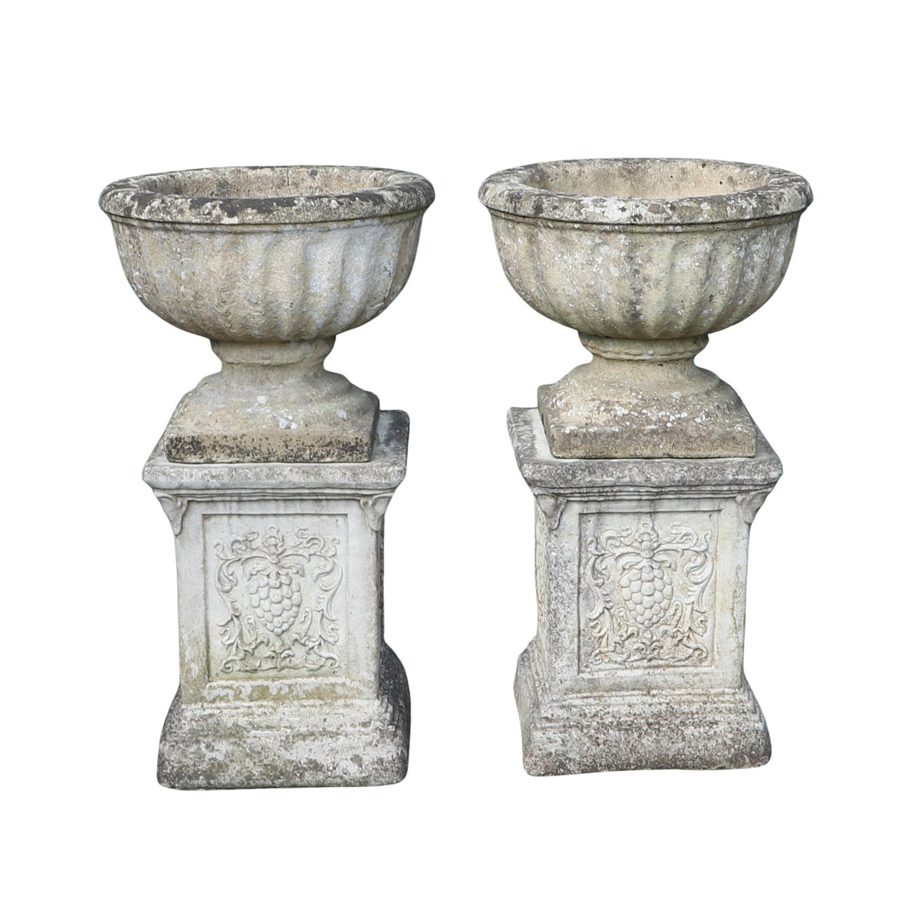 A PAIR OF RECONSTITUTED STONE URNS ON PLINTHS.