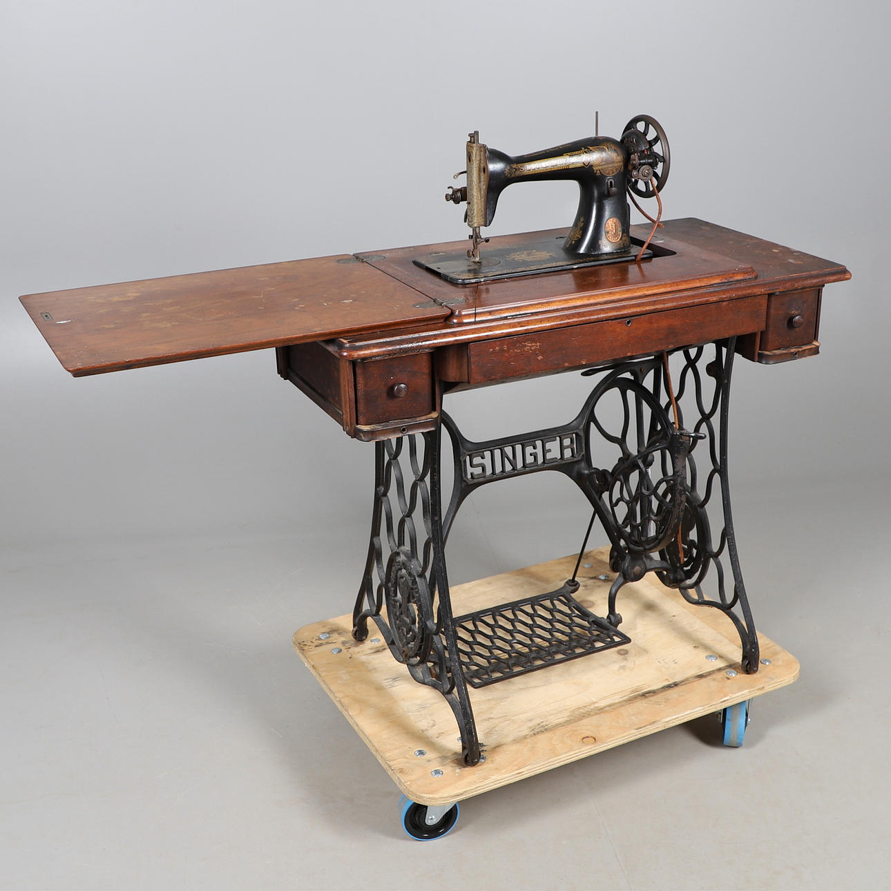 A TREADLE SEWING MACHINE ON CAST IRON BASE.