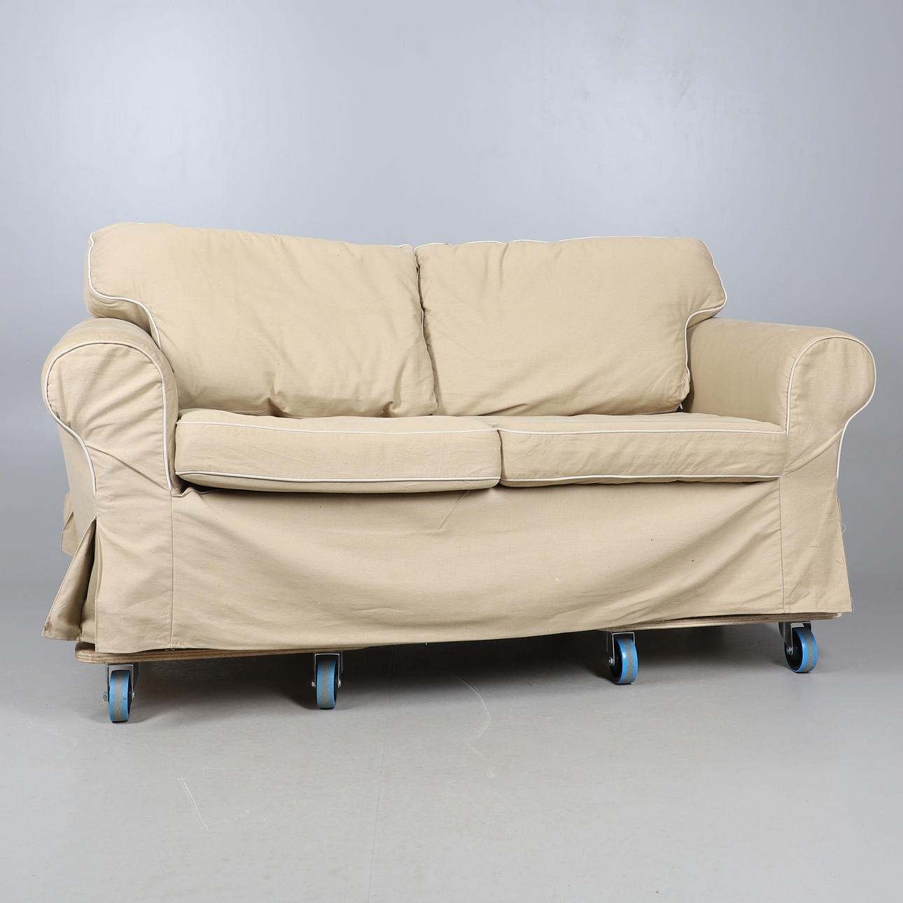 EIN MODERNES CREMEFARBENES ZWEISITZER-SOFA.