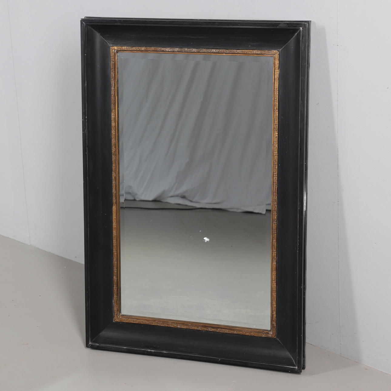 A MODERN EBONISED AND GILT WALL MIRROR.