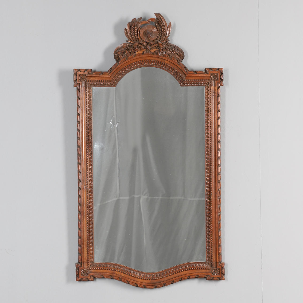 A FRENCH CARVED WALNUT WALL MIRROR.