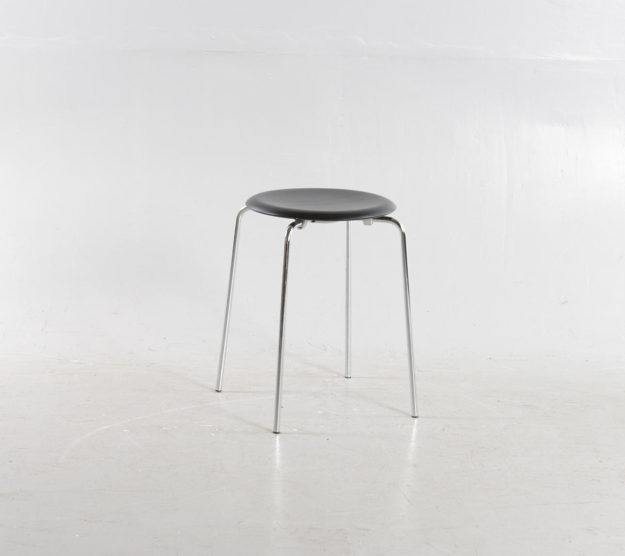 ARNE JACOBSEN. “Dot”, taburet med ben af forkromet stål, sæde af sortlakeret træ. Udført og mærket hos Fritz Hansen, model 3170 - Brown Label.