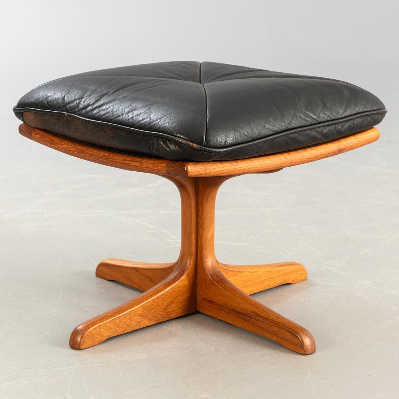 teak ottoman with leather upholstery.