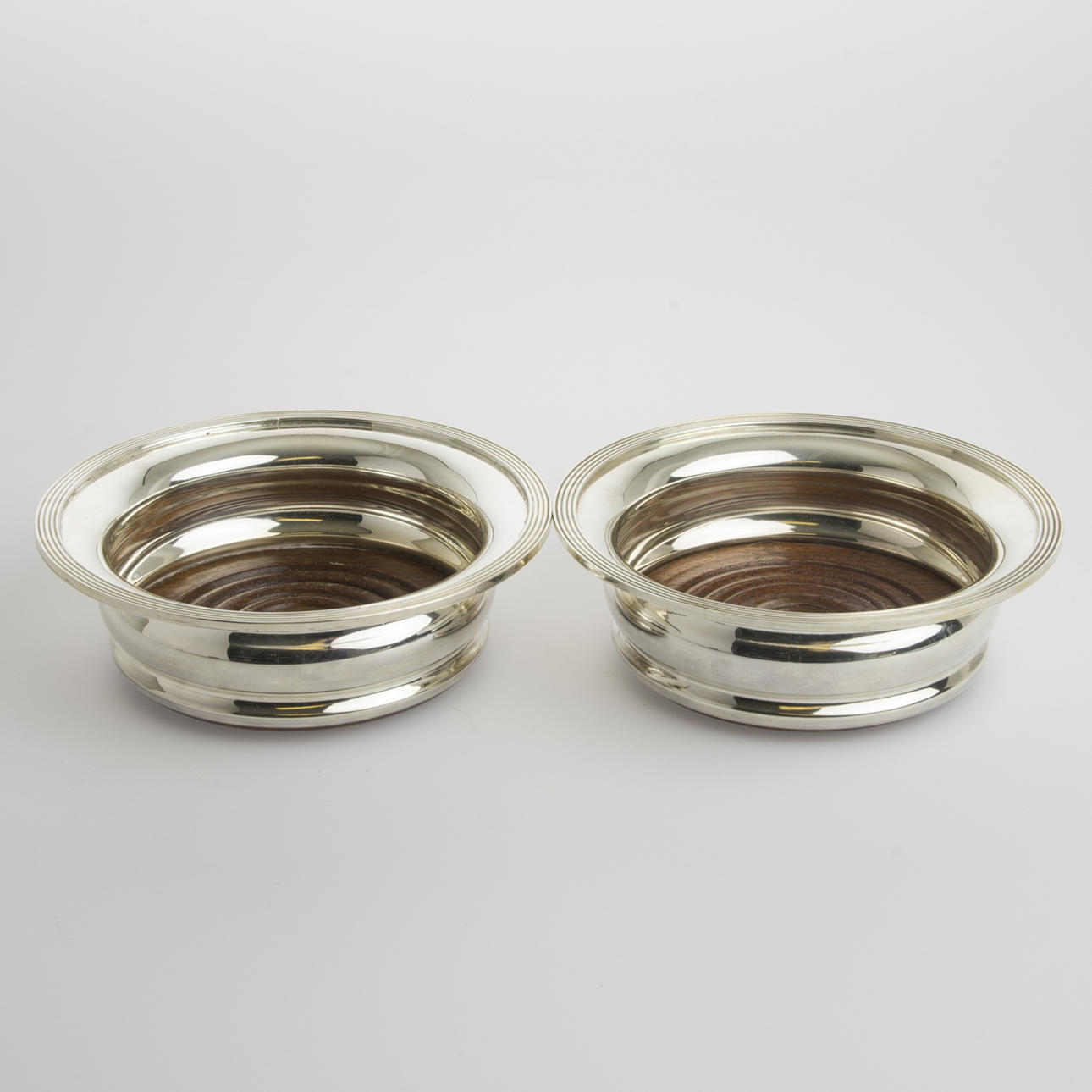 COASTERS, 1 par för flaskor, nysilver med träbotten, England.