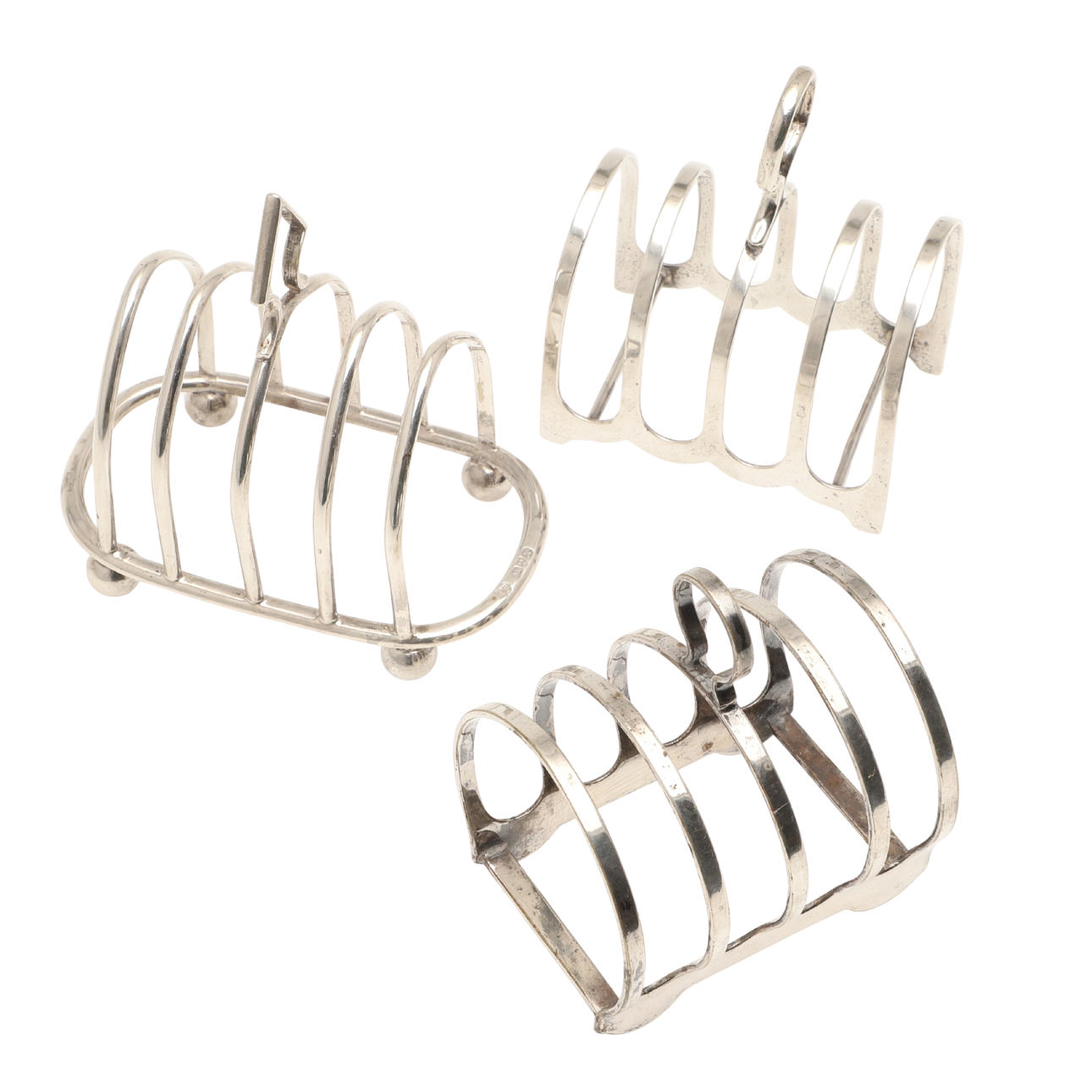 TWO EARLY 20TH CENTURY SILVER TOAST RACKS AND ANOTHER SILVER PLATED.