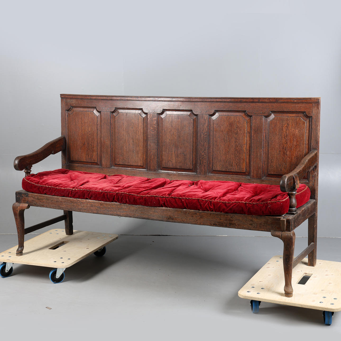 A GEORGE III OAK OPEN ARM PANEL BACK SETTLE.