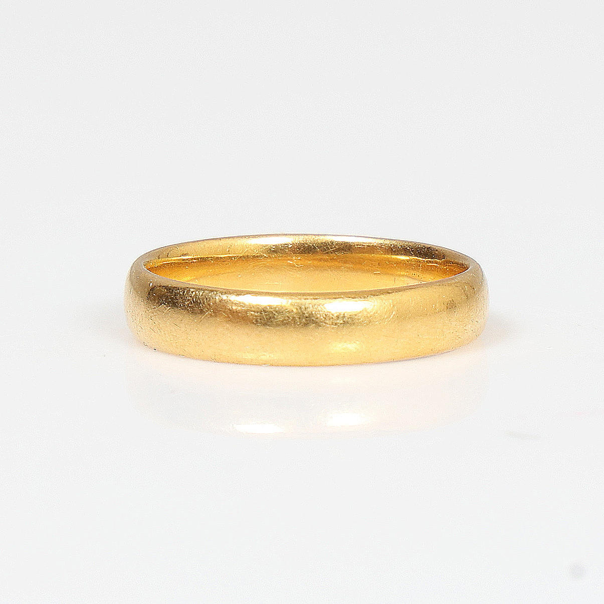 A YELLOW METAL WEDDING RING.