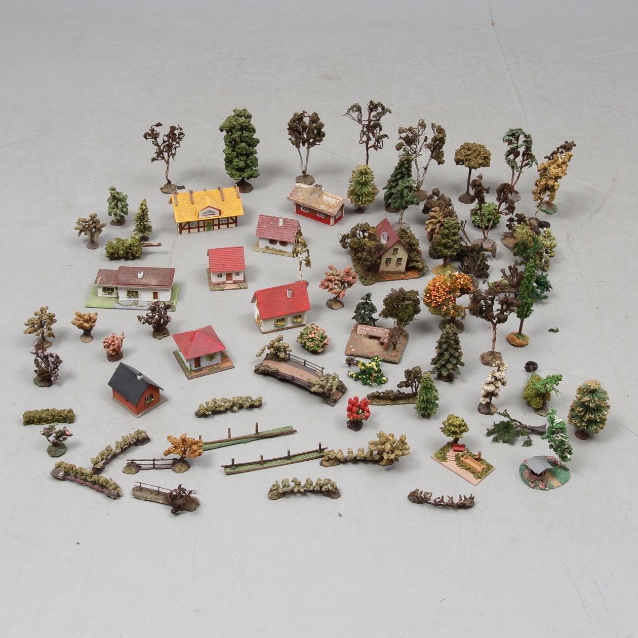 MODELLTÅG tillbehör i form av hus, buskar och träd.