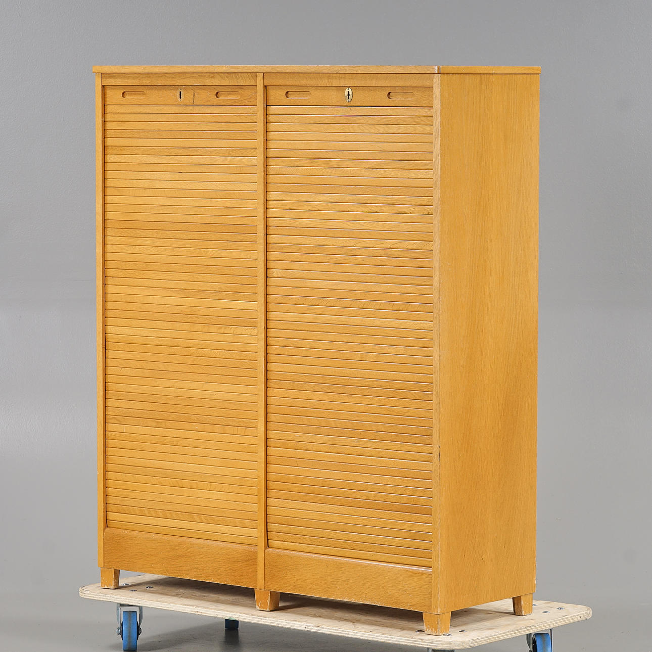A mid 20th century oak filing cabinet with blinds.