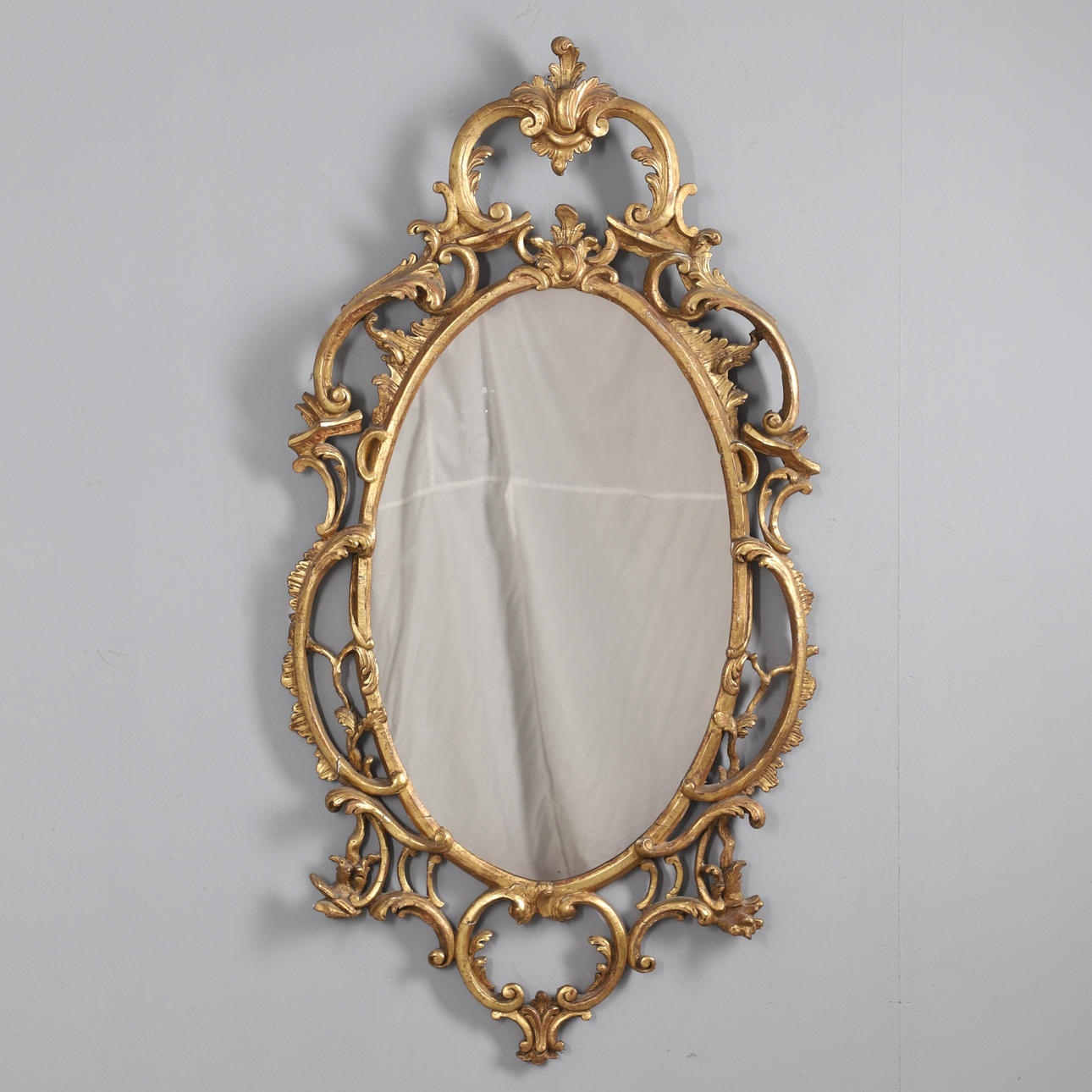 A ROCOCO STYLE GILT GESSO WALL MIRROR.