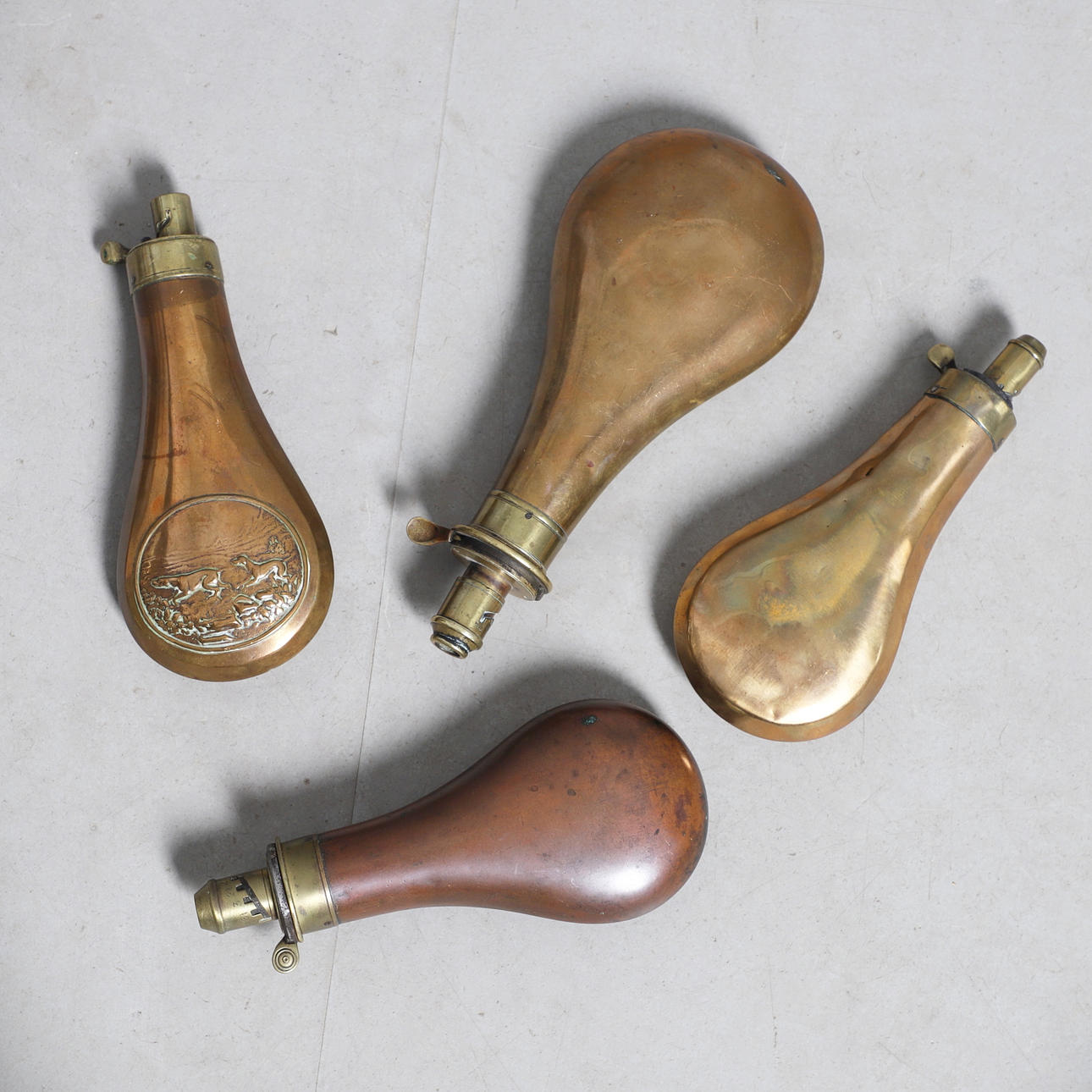 A COLLECTION OF FOUR VICTORIAN AND LATER COPPER BODIED POWDER FLASKS ...