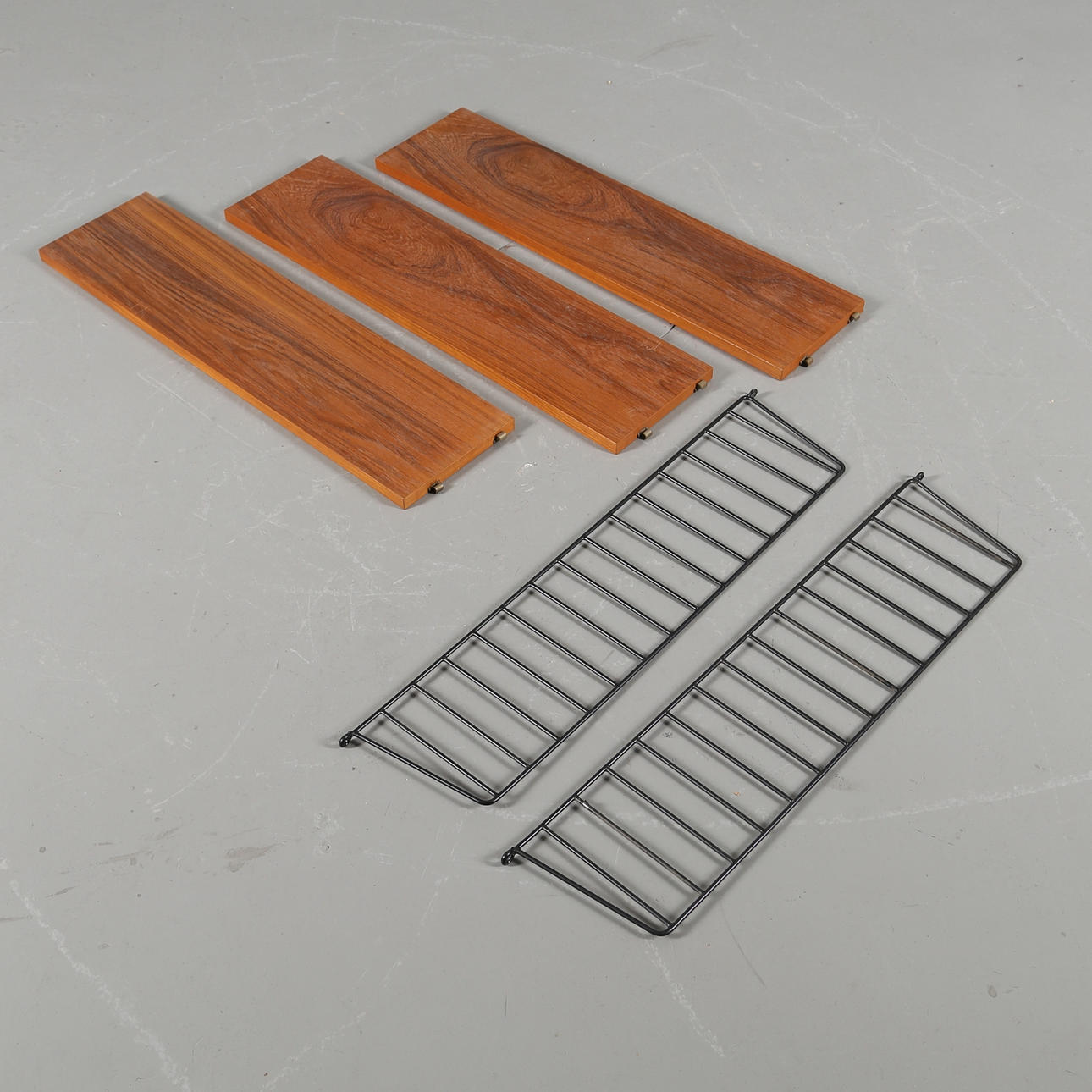 NILS STRINNING. Stringhylla med 3 hyllplan i teakfanér med plastöverdragna ståltrådsgavlar.