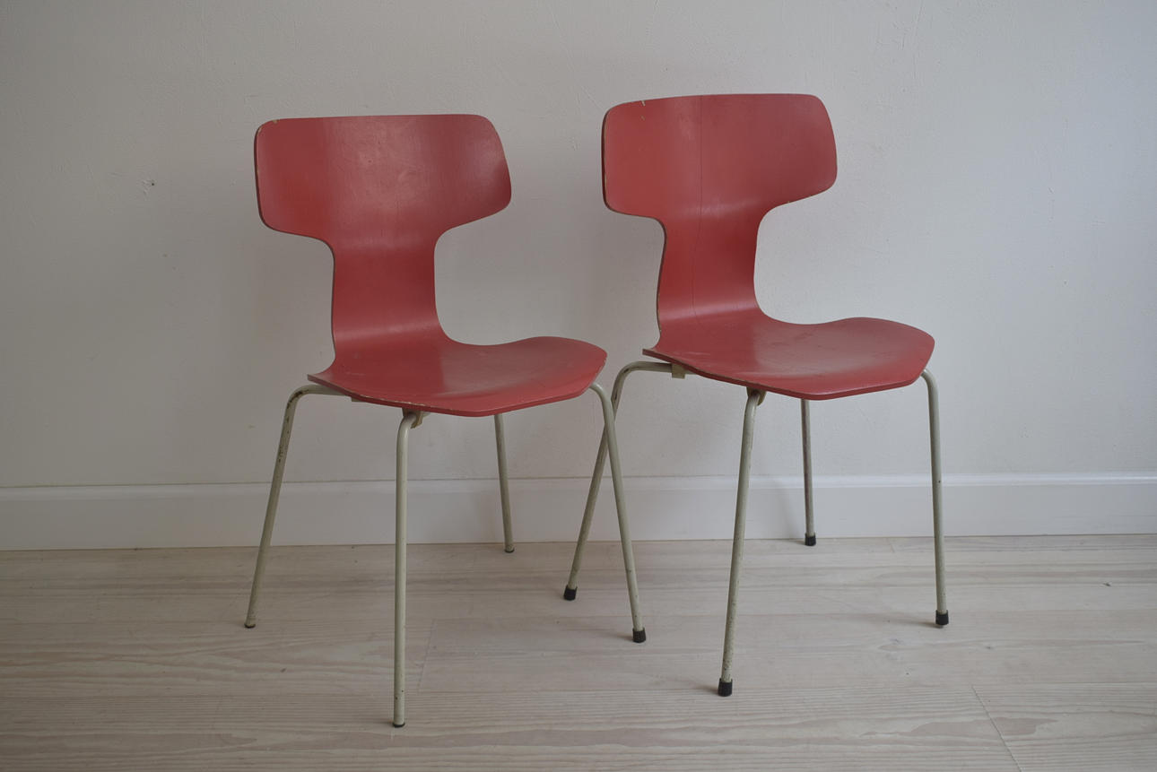 ARNE JACOBSEN. Ett set med två T-stolar i rött, tillverkad av Fritz Hansen 1971.