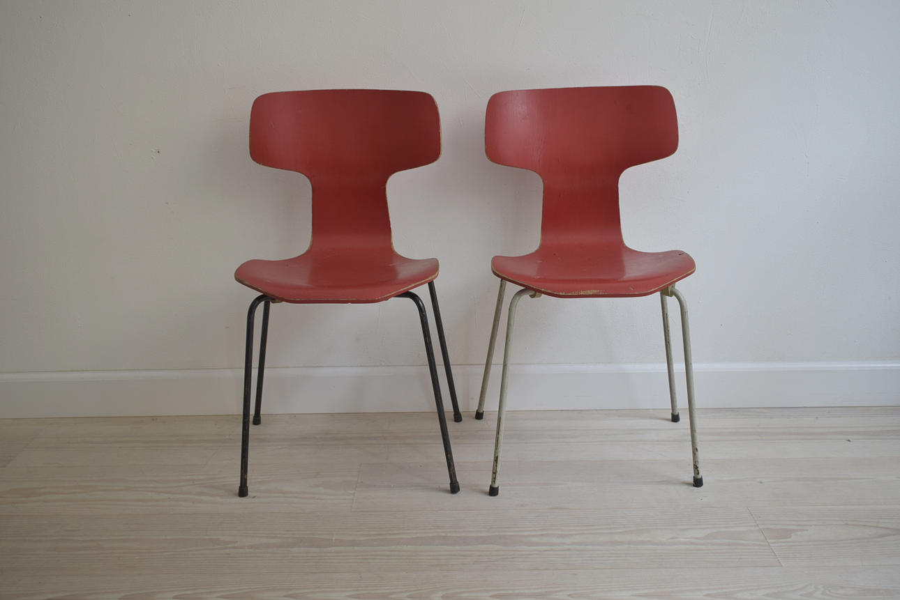 ARNE JACOBSEN. Ett set med två T-stolar i rött, tillverkad av Fritz Hansen i 1970.