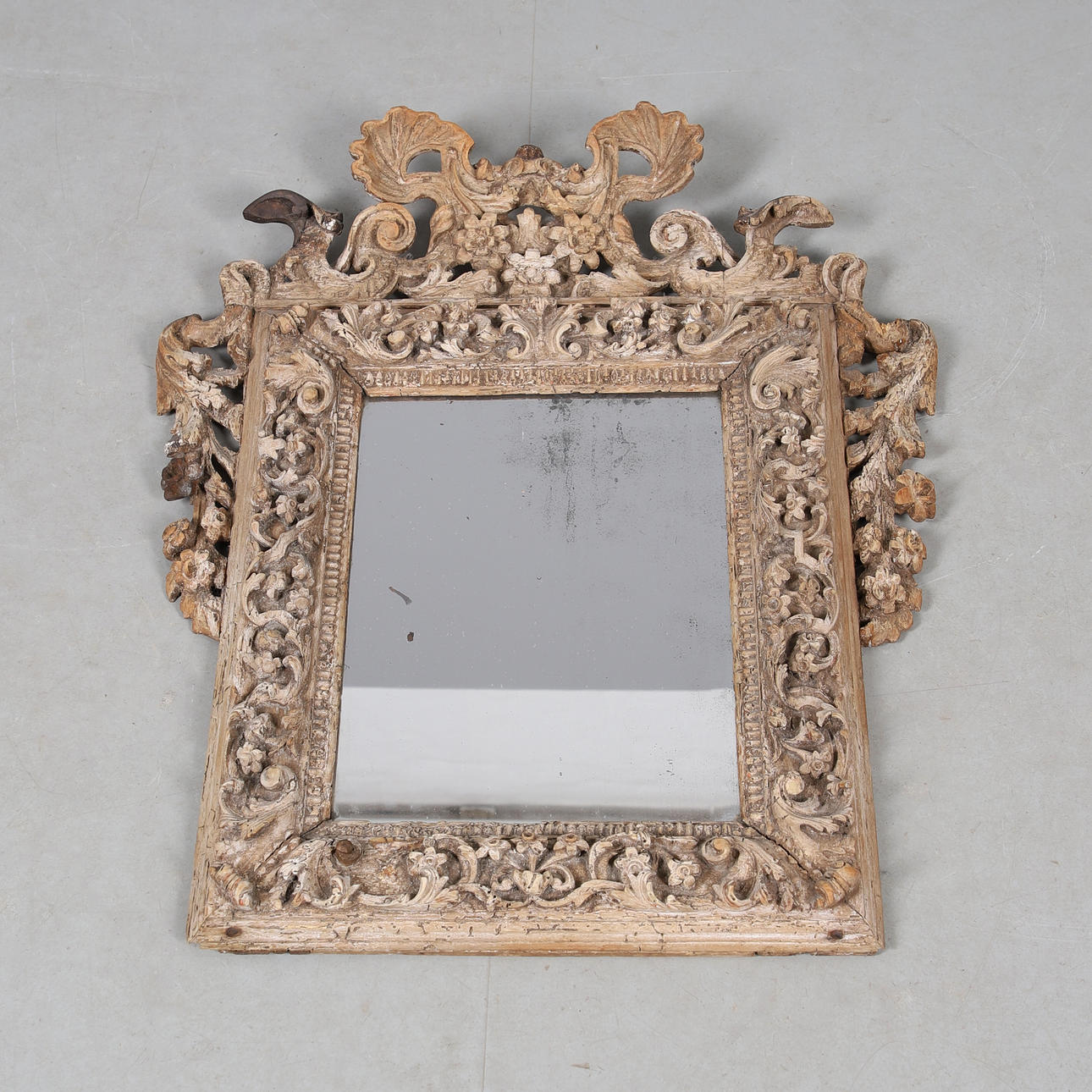A CONTINENTAL CARVED WOOD FRAMED WALL MIRROR.