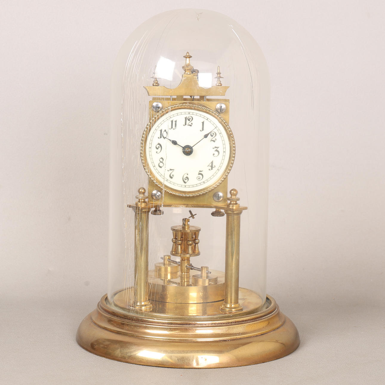 A BRASS ANNIVERSARY CLOCK UNDER DOME.