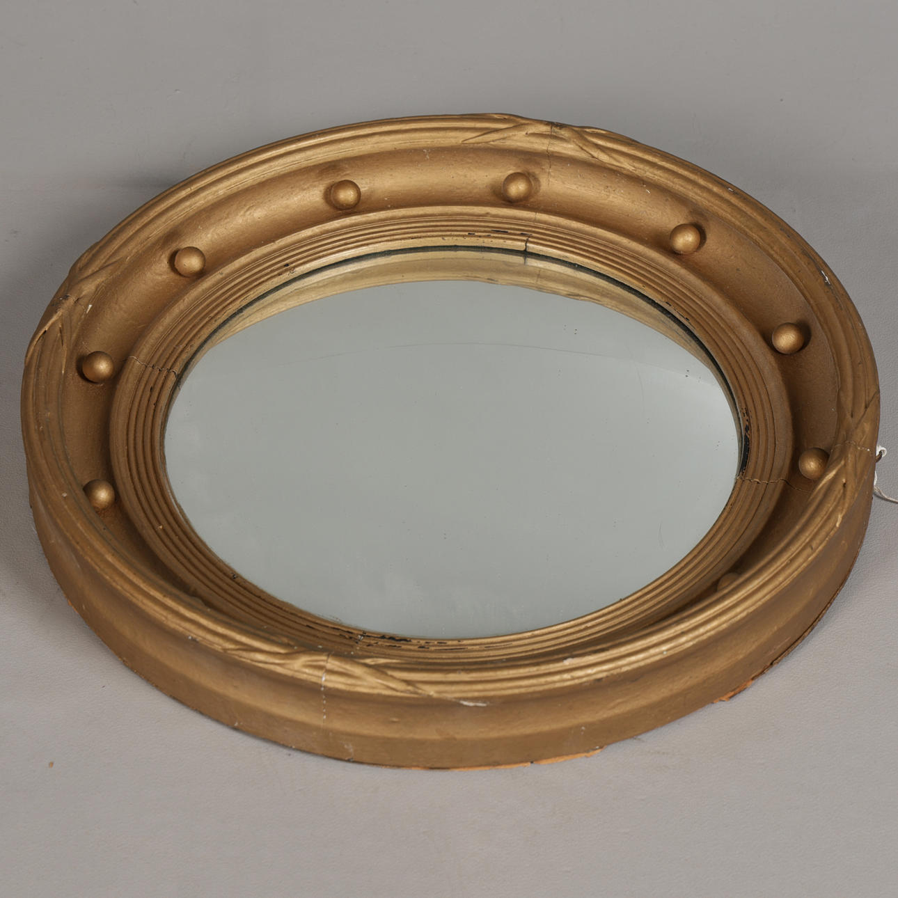 A REGENCY STYLE GILT GESSO CONVEX MIRROR.