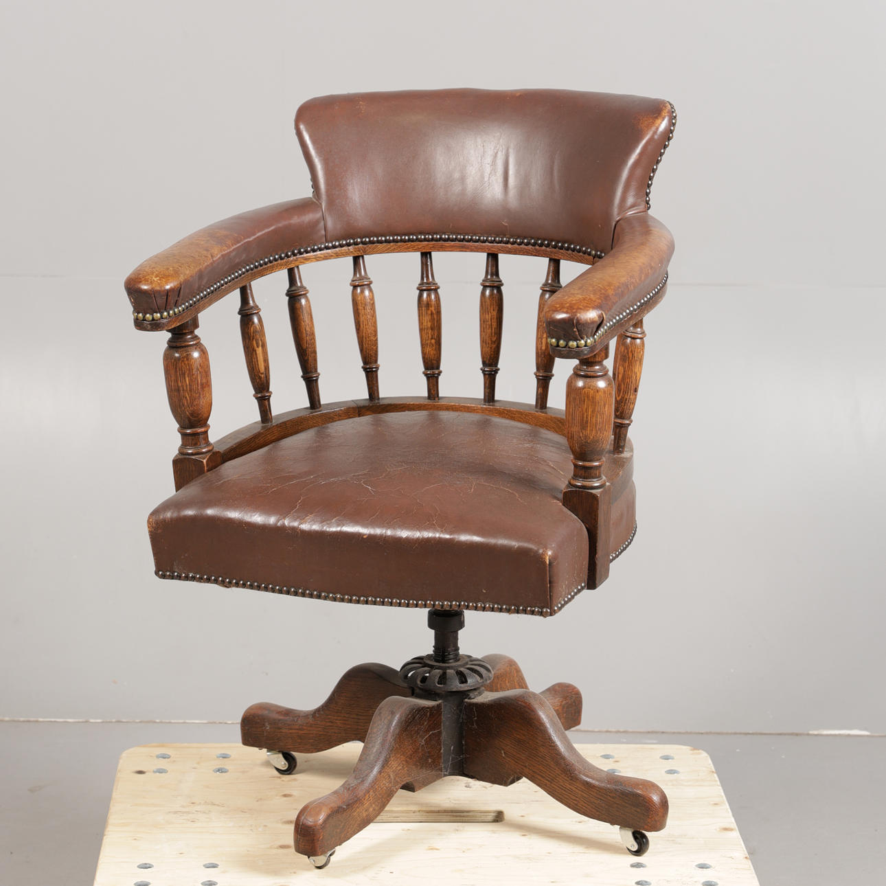 AN EARLY TO MID 20TH CENTURY OAK AND LEATHER REVOLVING DESK CHAIR ...