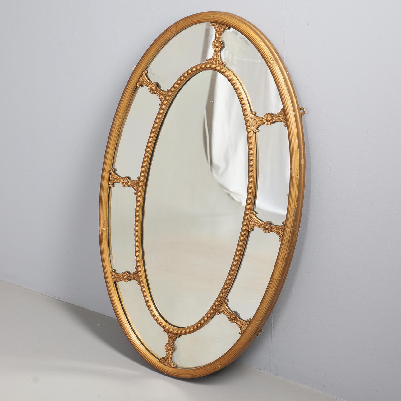 AN OVAL MULTI-PLATE WALL MIRROR.