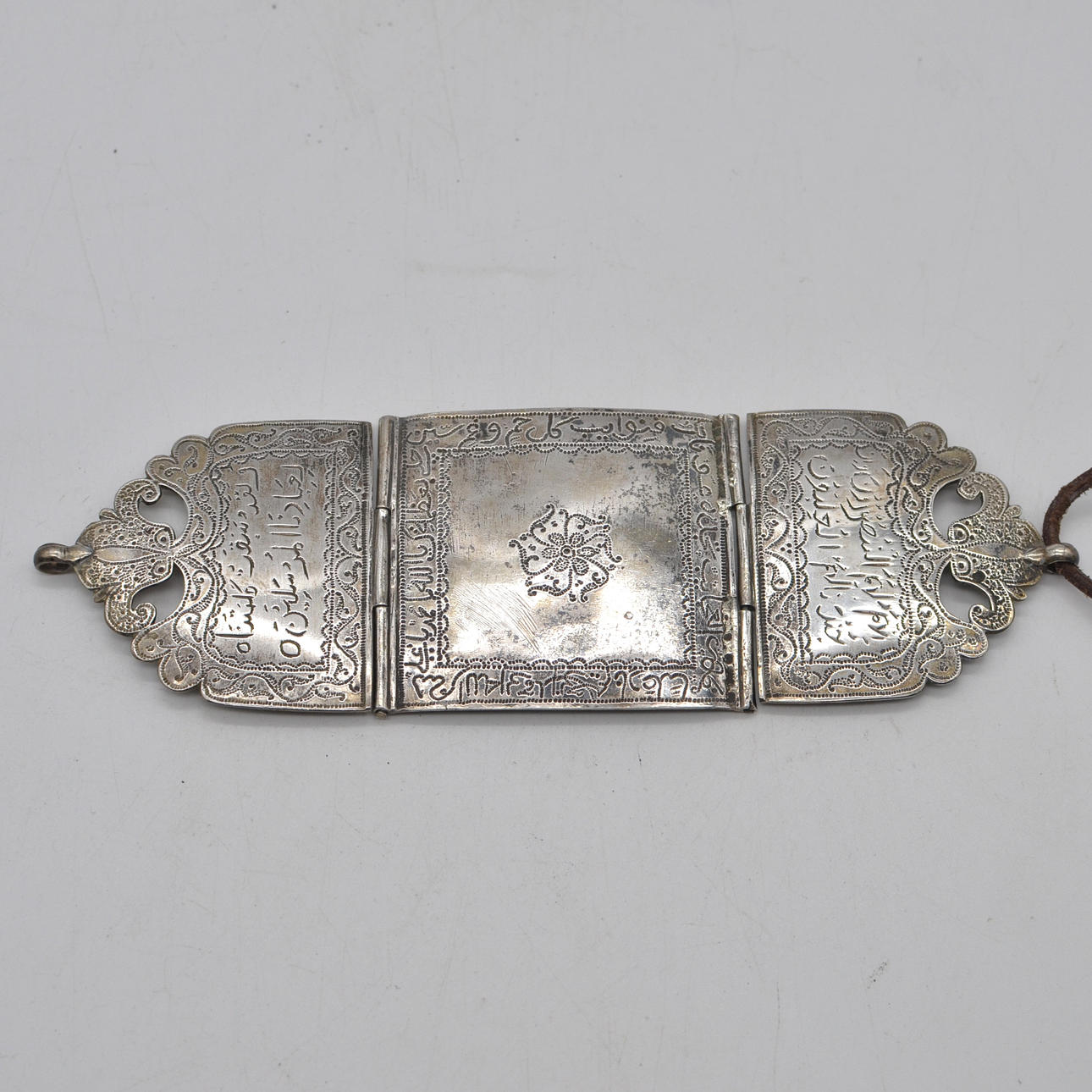 ANTIQUE SILVER TALISMAN, ARABIC SCRIPT DECORATION (HAND-DRIVEN), EXCERPT FROM THE KORAN - SURAH AS-SAFFAT (37:171 —173), IN THREE PARTS, AROUND 1900.